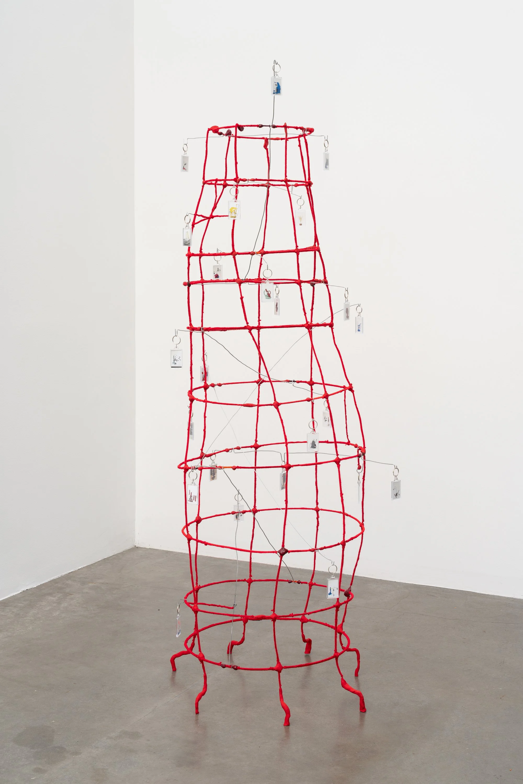 a wire tower wrapped in red yarn, with key chains hanging from bent wires