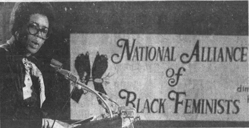    A black-and-white Image of       Brenda Eichelberger, Founding Member and Chairwoman of the National Alliance of Black Feminists.    Eichelberger is positioned in front of a National Alliance of Black Feminists Sign. Source:    Veteran Feminists o