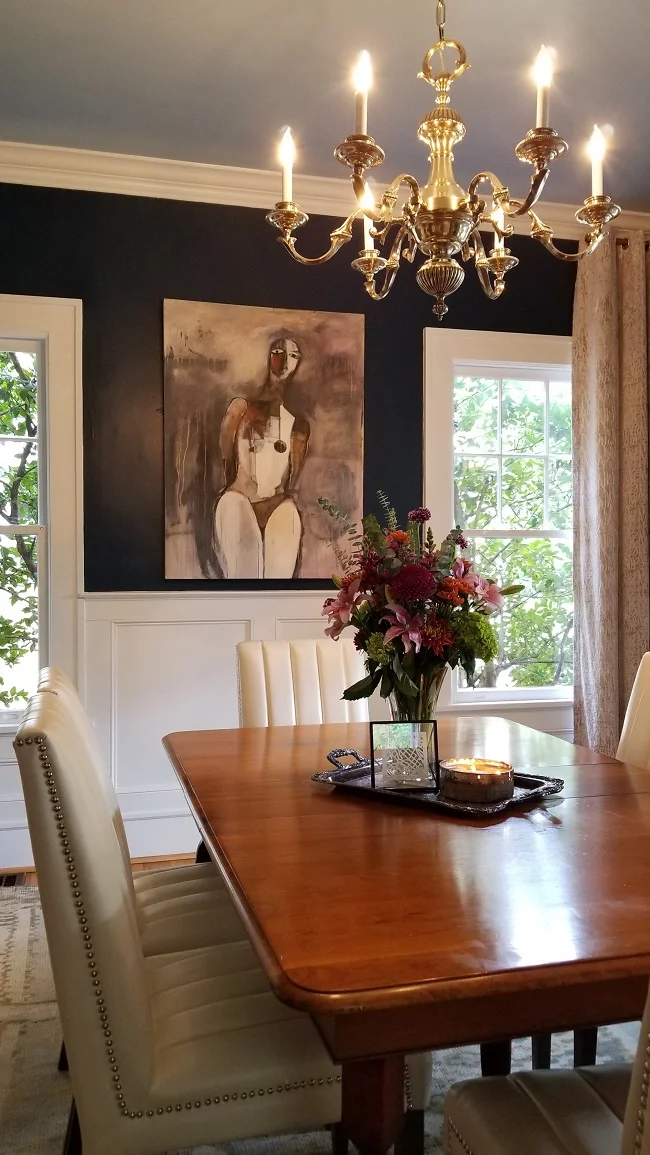 Dining room with wooden table, modern artwork on the wall and chandelier