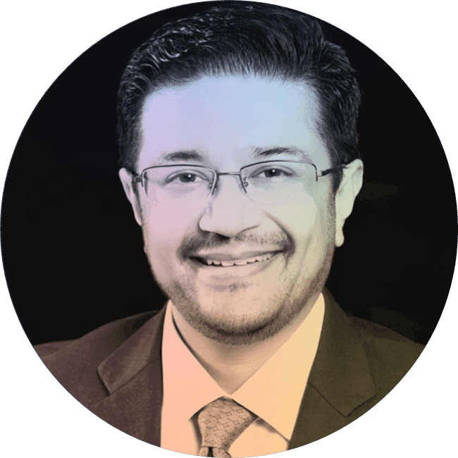 Headshot of a smiling man with glasses and dark hair, wearing a suit and tie, against a black circular background.