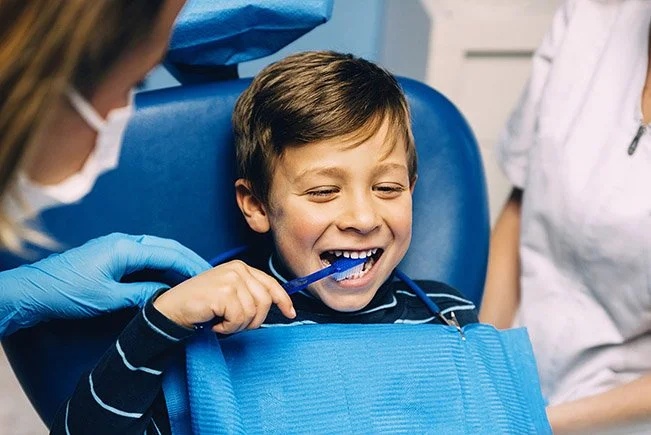 Imagen de un niño practicando el uso de un cepillo dental en la oficina de el dentista