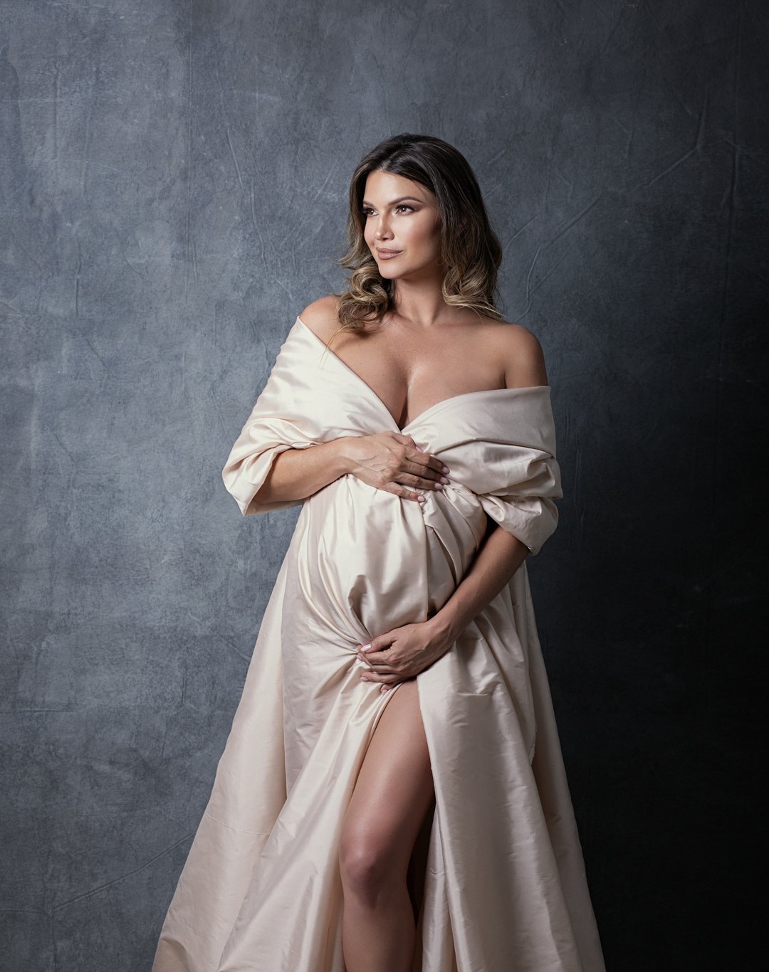 Maternity photoshoot by Photography Miami Pilar Andujar captures a pregnant woman in a nude dress posing gracefully for a portrait.