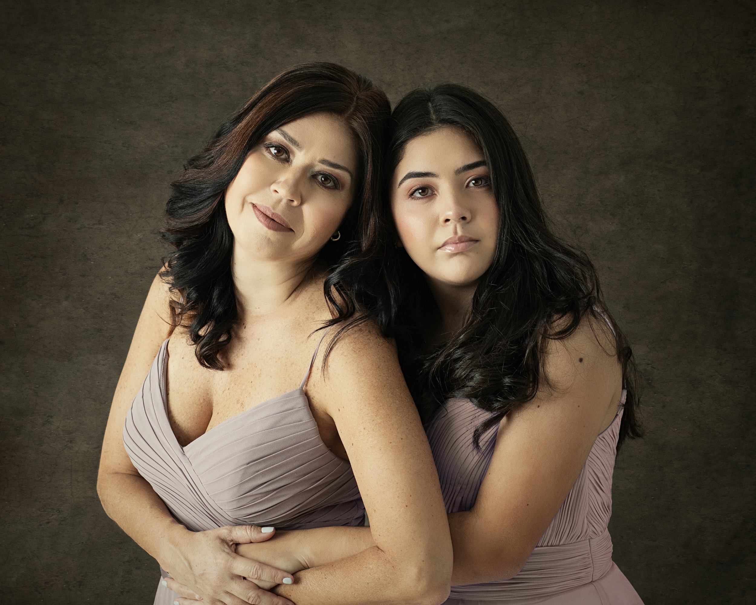 Two women in elegant dresses posing for a portrait during a photoshoot by Pilar Andujar in Miami.