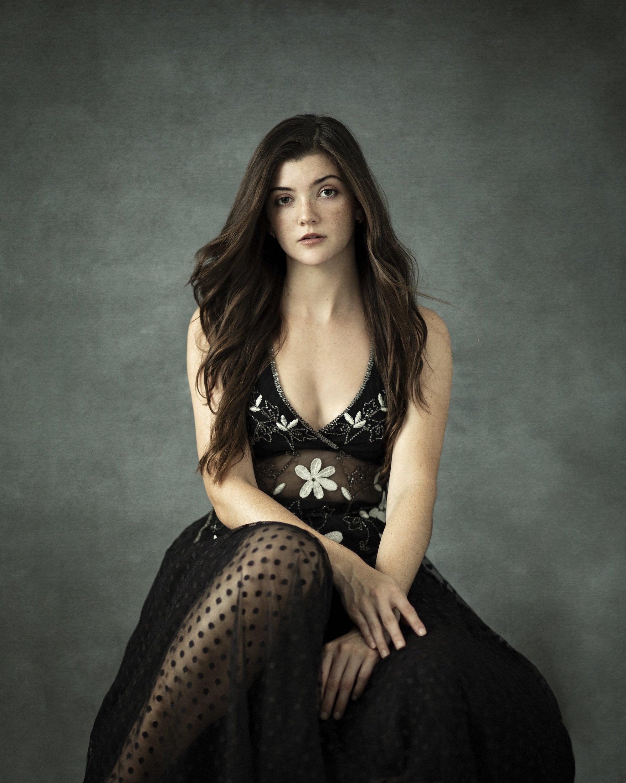 A woman in a black dress sitting on a chair during a photography Miami Pilar Andujar photoshoot.