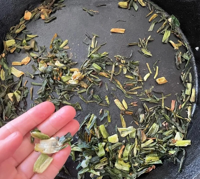 Chopped onion weed cooking in cast iron pan