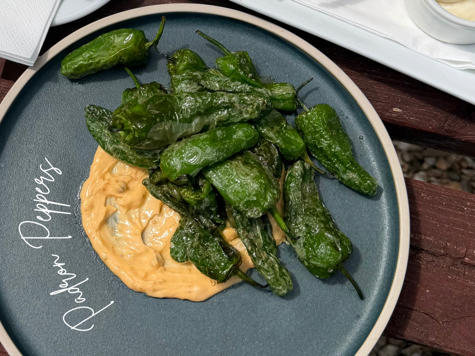 Green peppers with a creamy dipping sauce on a dark gray plate with the phrase 'Phew, peppers' written on it.