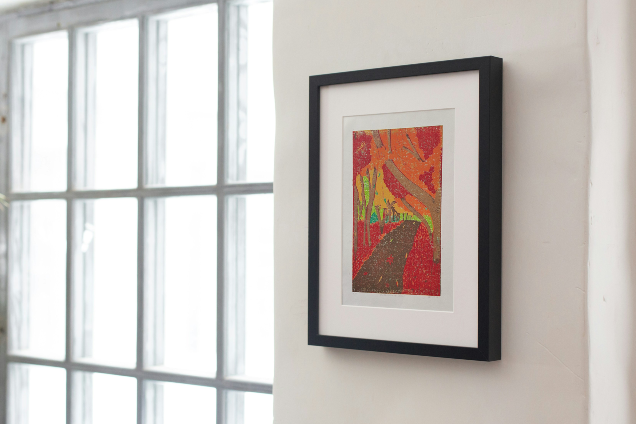 Mock Up of The Corridor of Colour Original Linocut in a black frame on a white wall by larger glass French doors