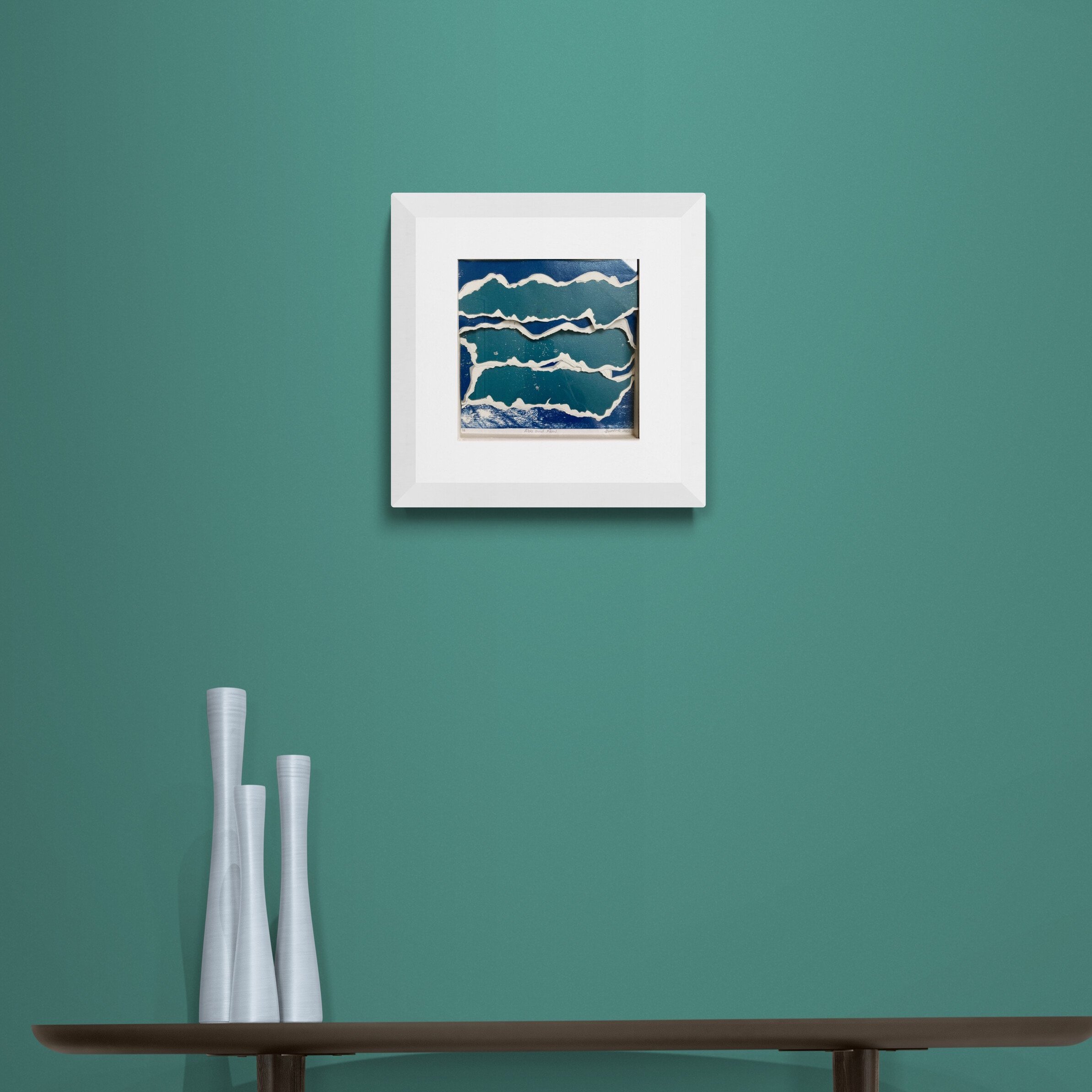 Ebb and Flow print collage framed in white box frame on green wall over a table