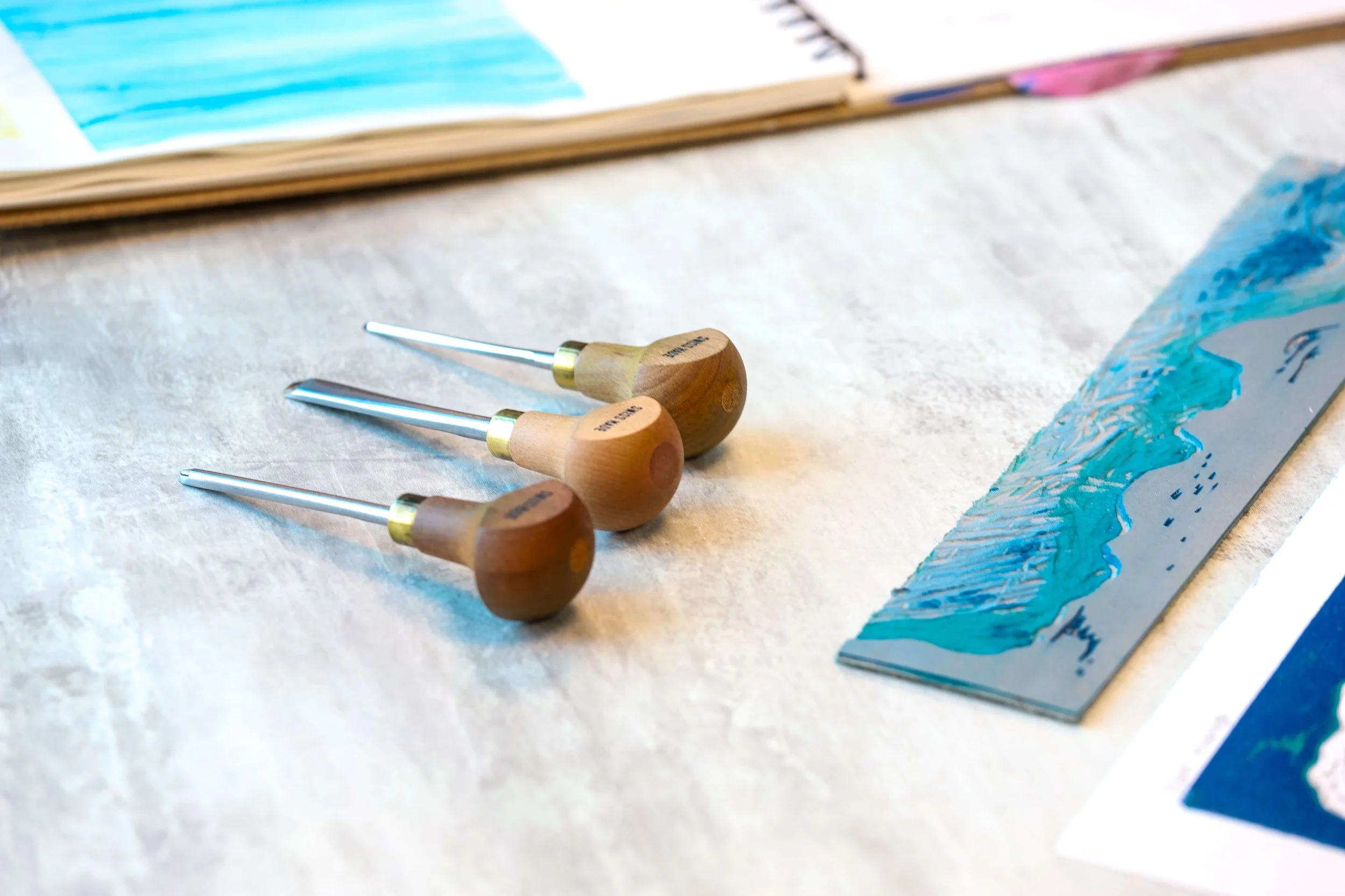 Pfeil gouge tools next to carved lino and small reduction print