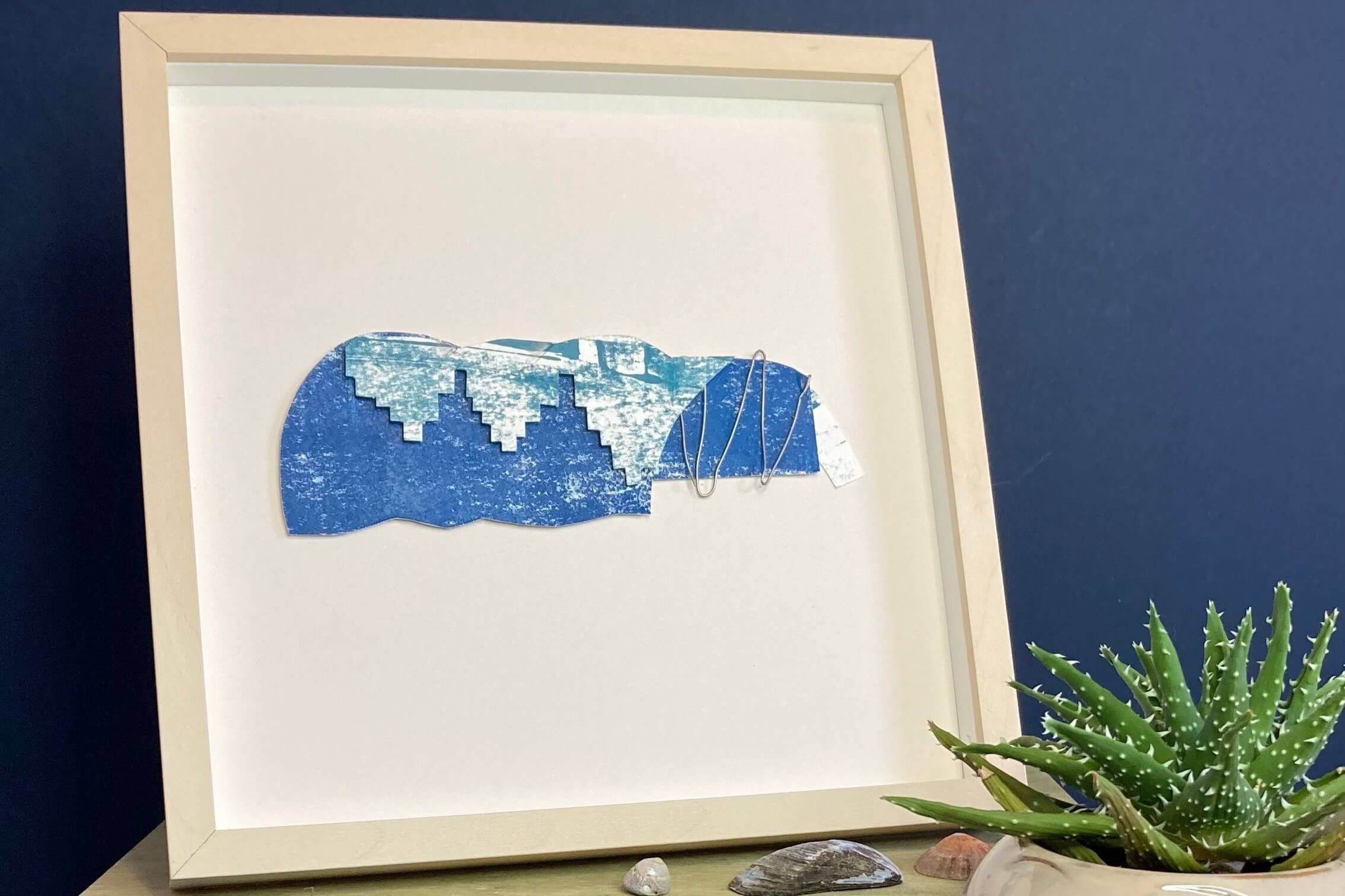 Framed Sage Gateshead Collage with wire on a wooden shelf
