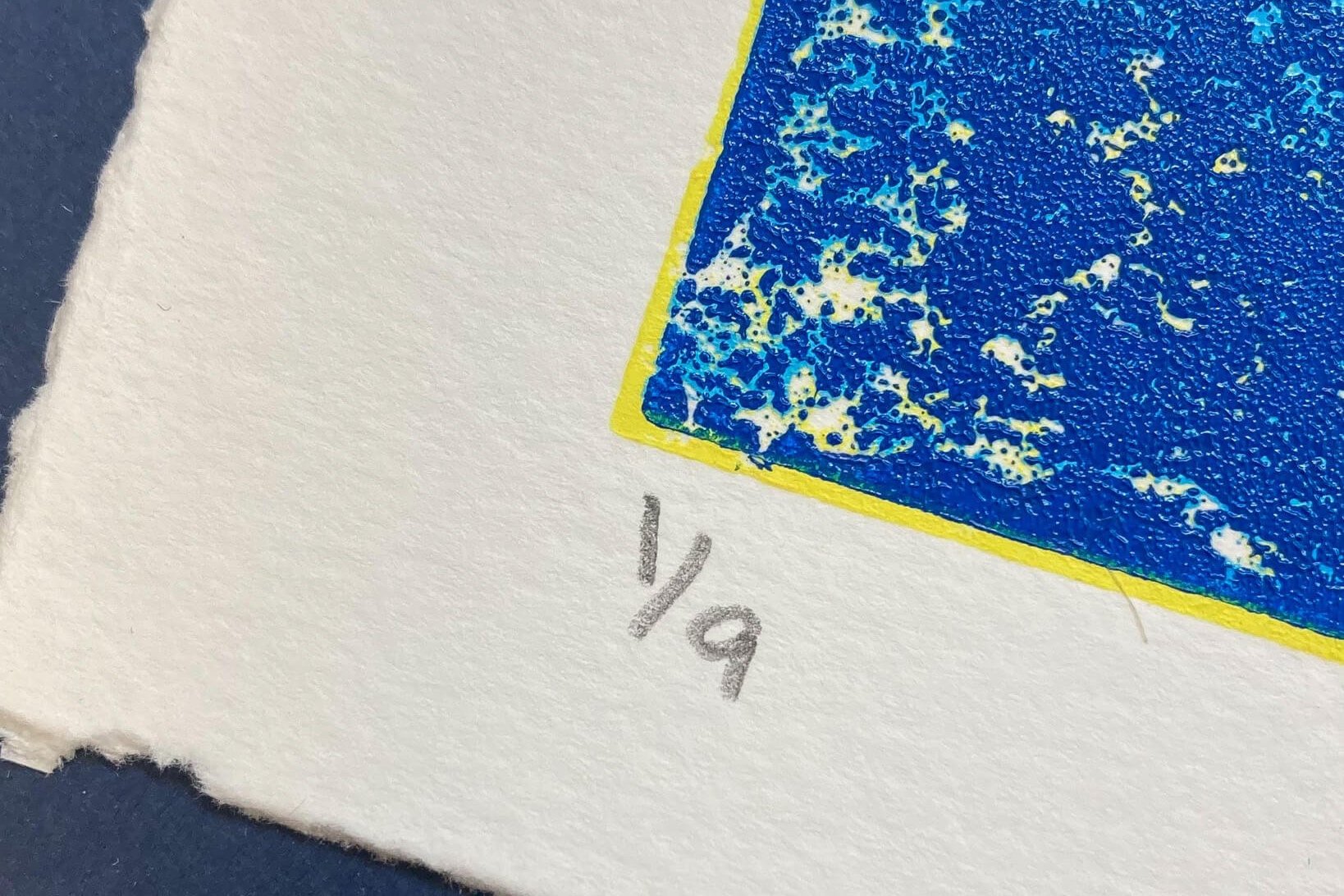 Close up of numbering '1 of 9' prints on Rush Tidal Wave Print in 5 blues and blended tangerine orange and lemon yellow
