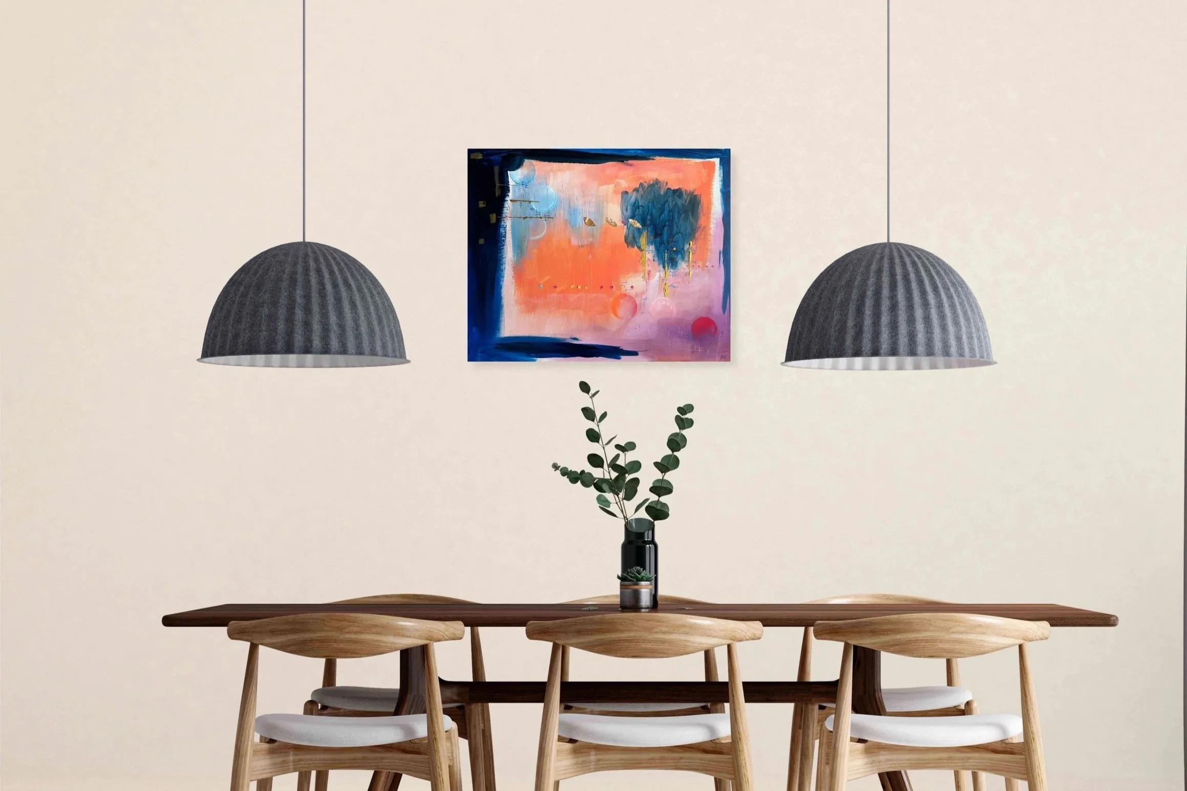 A dining room with a wooden table, matching chairs with white cushions, two black pendant lights, a potted plant, and a colorful abstract painting on a plain white wall.