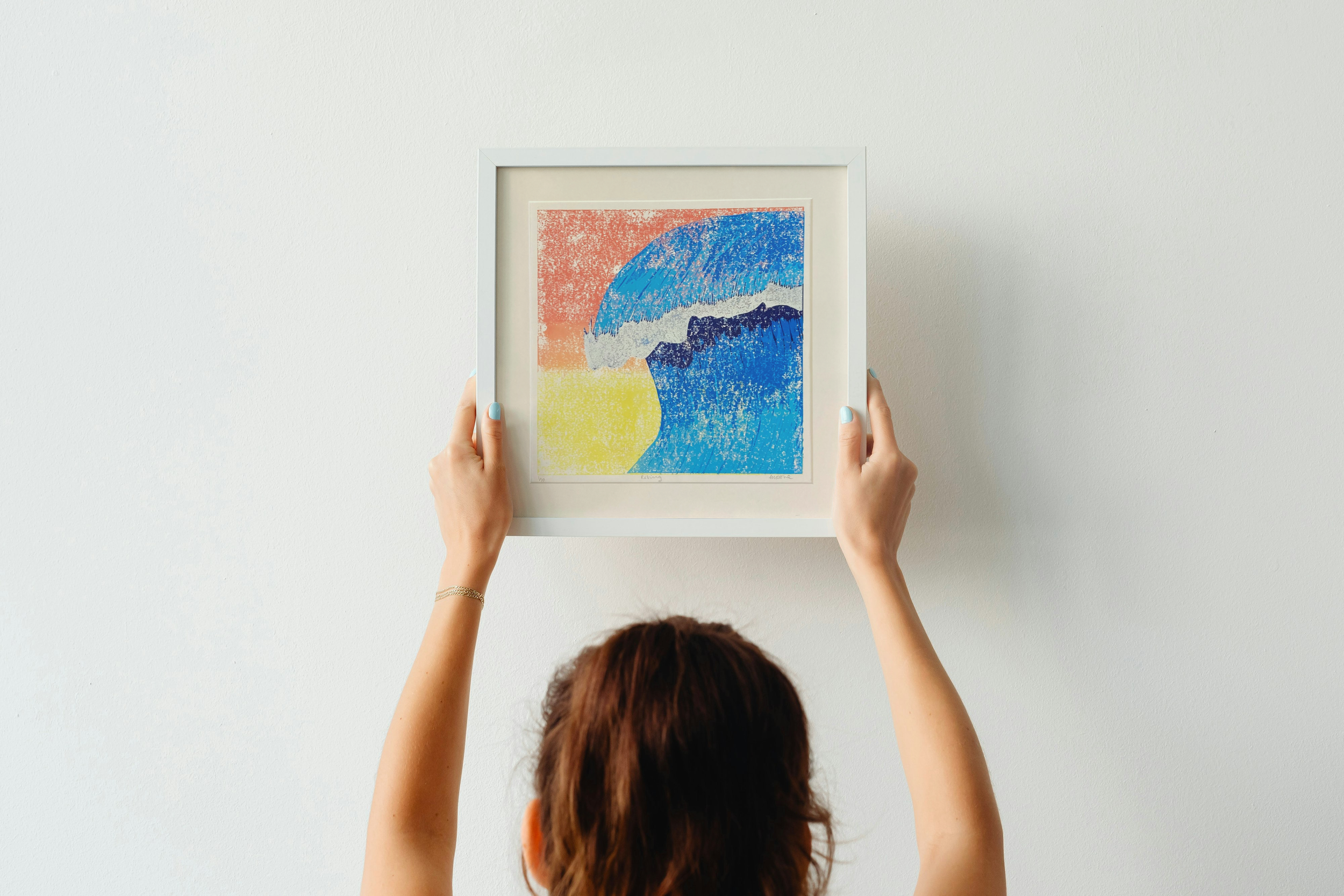 Rising in a simple white being hung on a soft white wall by a brunette.png