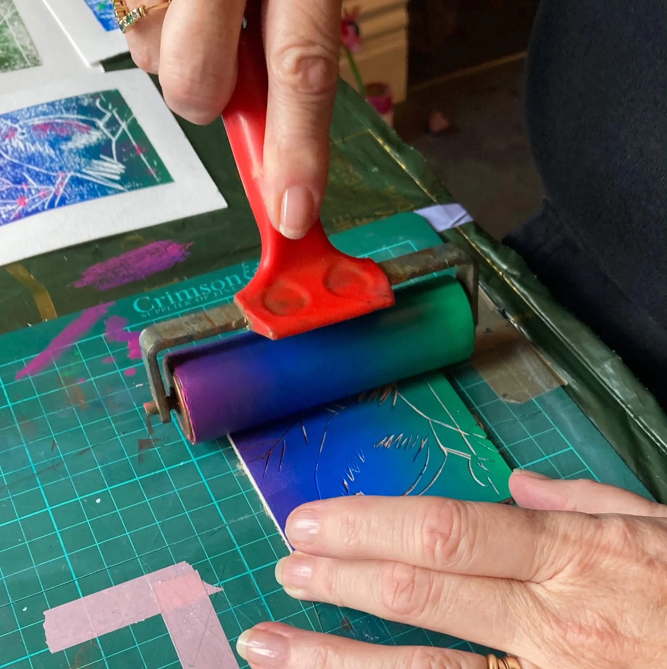 hands holding an inking roller and inking a blended colour onto a lino block