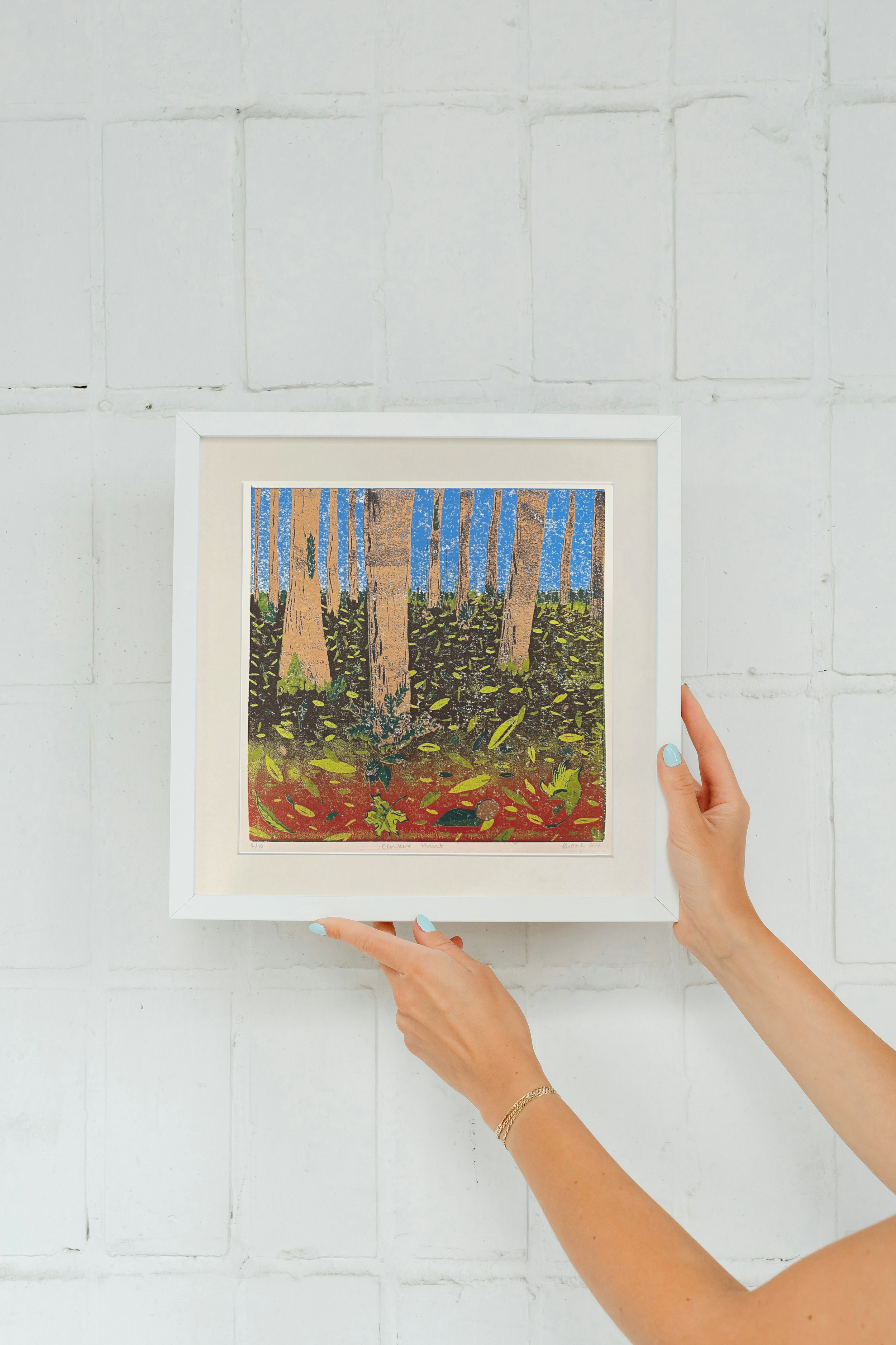 Conker Hunt Linocut in white frame against brick wall.png