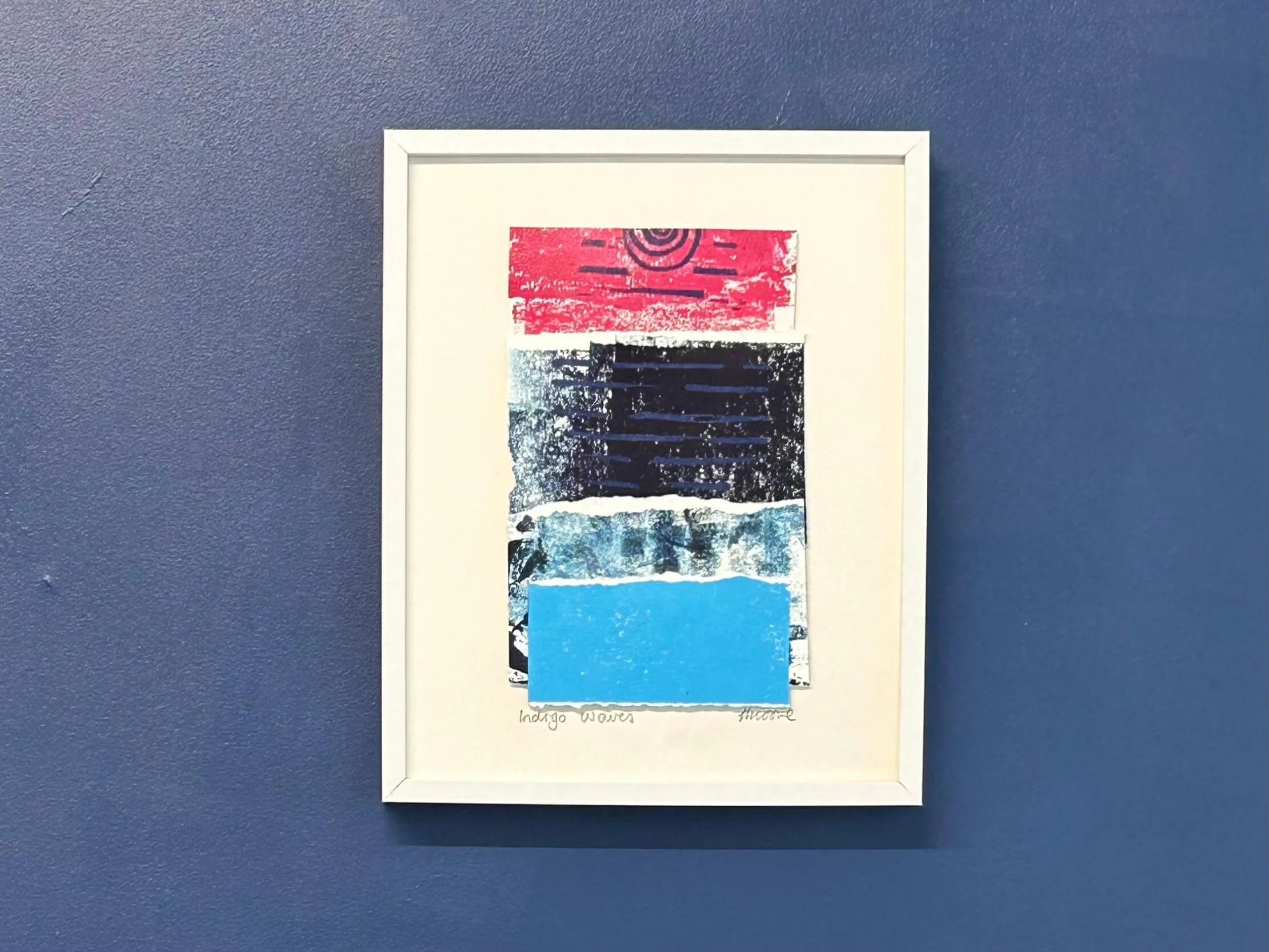 Turquoise, navy and hot pink mixed media collage and print in white frame on navy wall