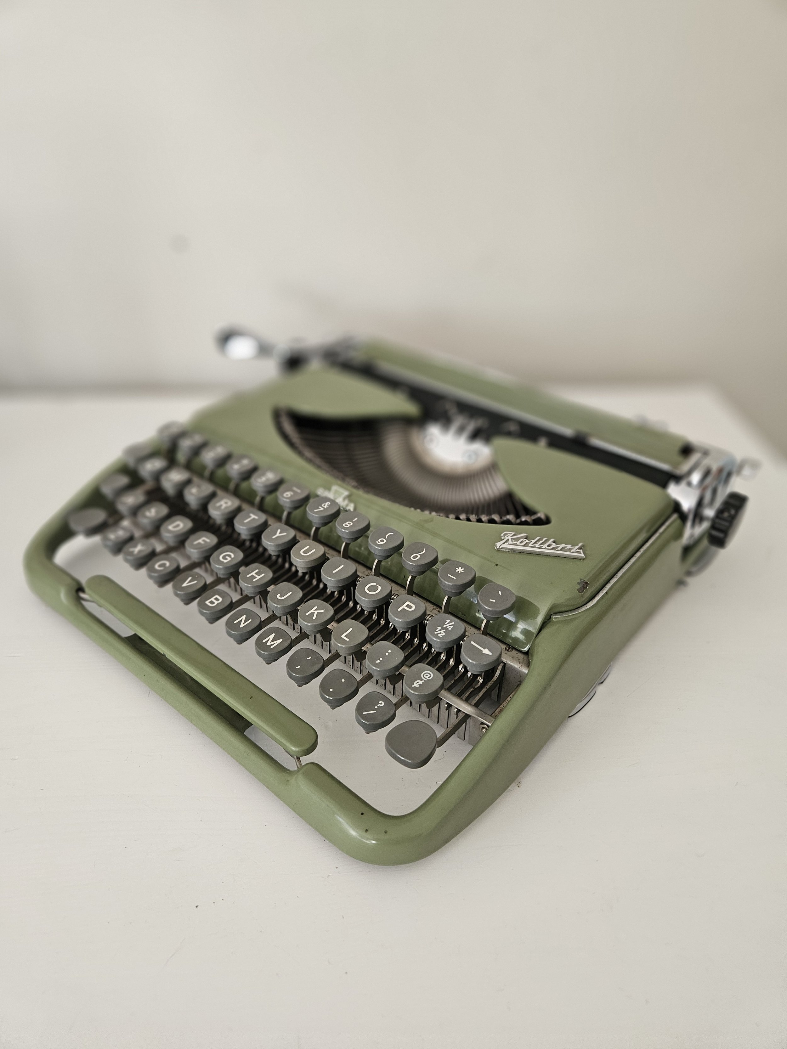Restored Groma Kolibri ultra-portable typewriter in olive green with gray keys.