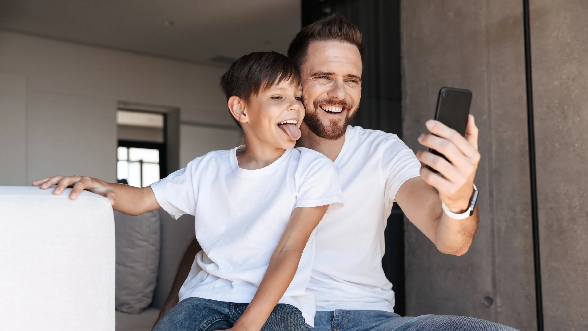 cheerful-young-man-father-dad-using-mobile-phone-2NQM7HD.jpg