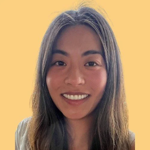 A young woman with long, straight hair smiling at the camera against a solid yellow background.