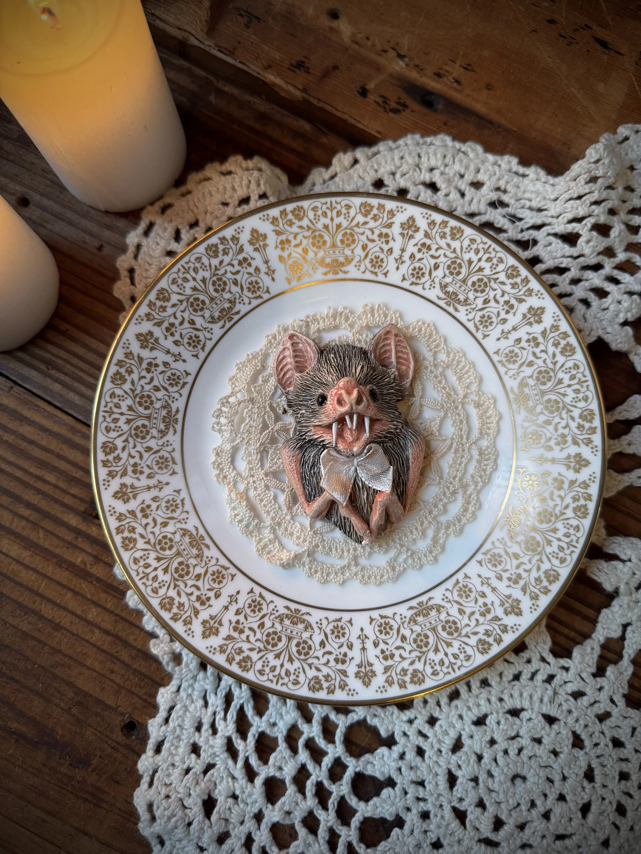 handmade faux taxidermy clay carved bats set on vintage teacup plates with vintage textile details