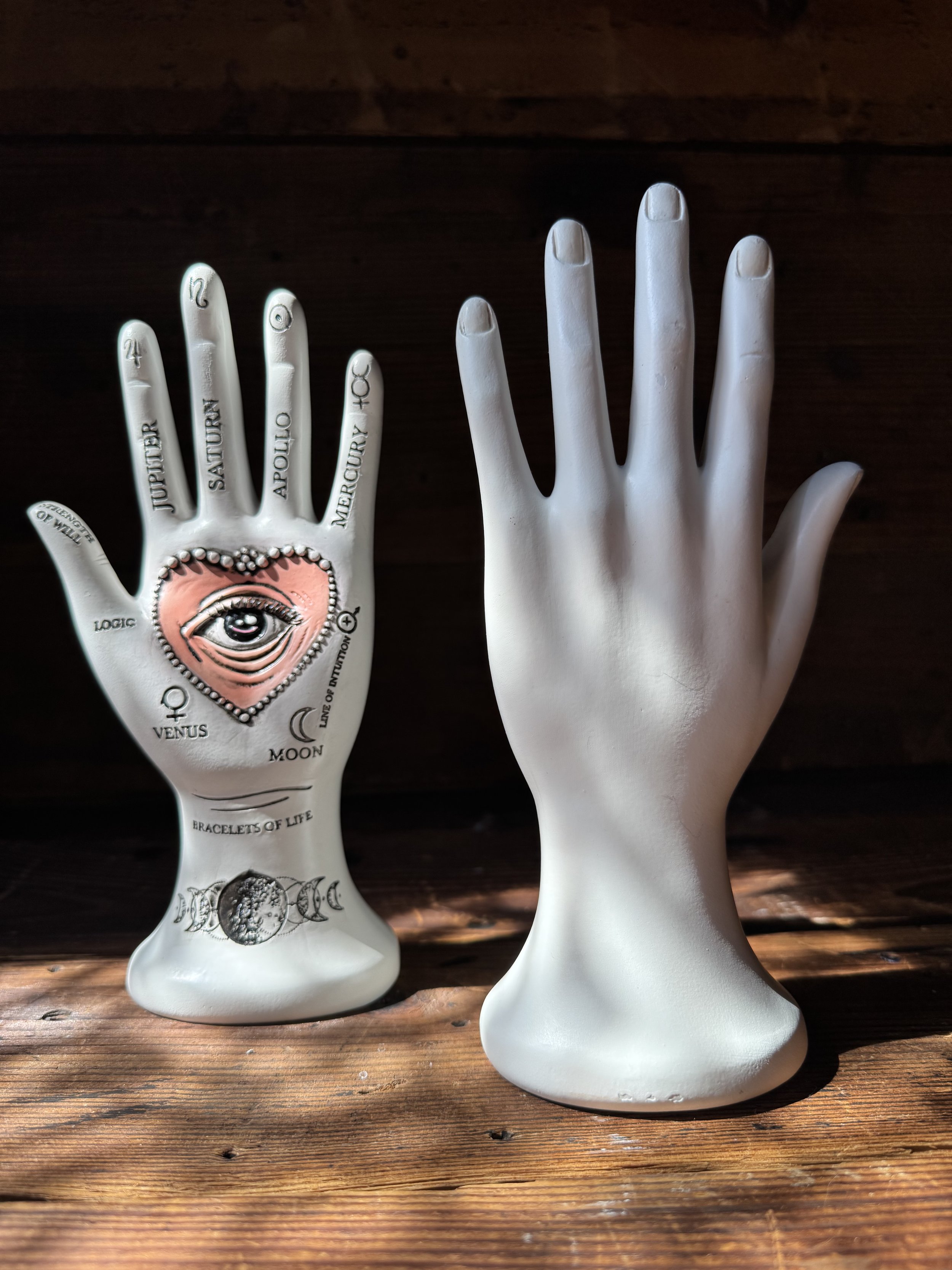 A white palmistry hand with all the meridians and a pink heart in the center with an all-seeing eye