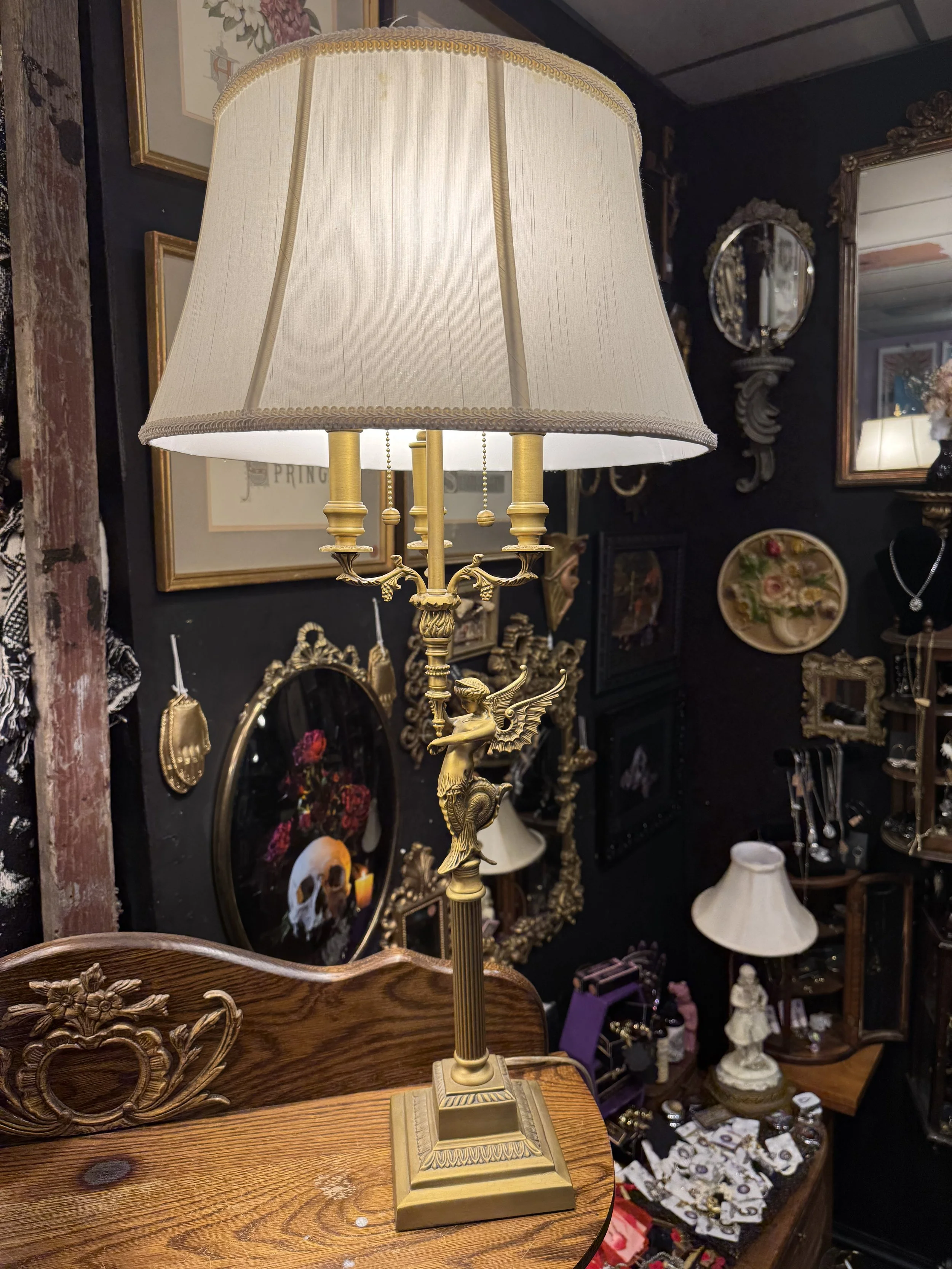 Antique gilded siren lamps with a white shade and a wooden base. Dual lightbulbs with pull chain.