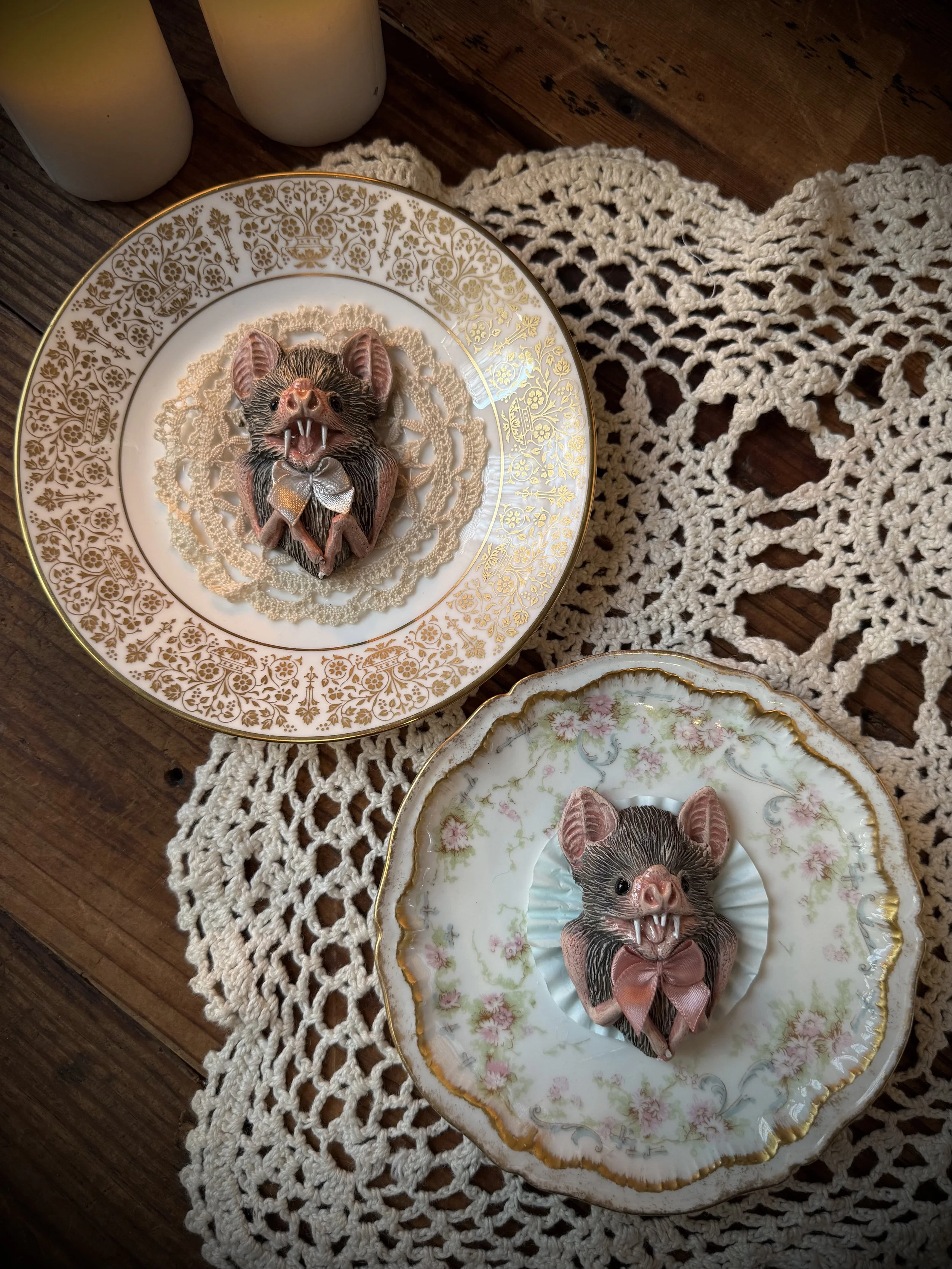 handmade faux taxidermy clay carved bats set on vintage teacup plates with vintage textile details