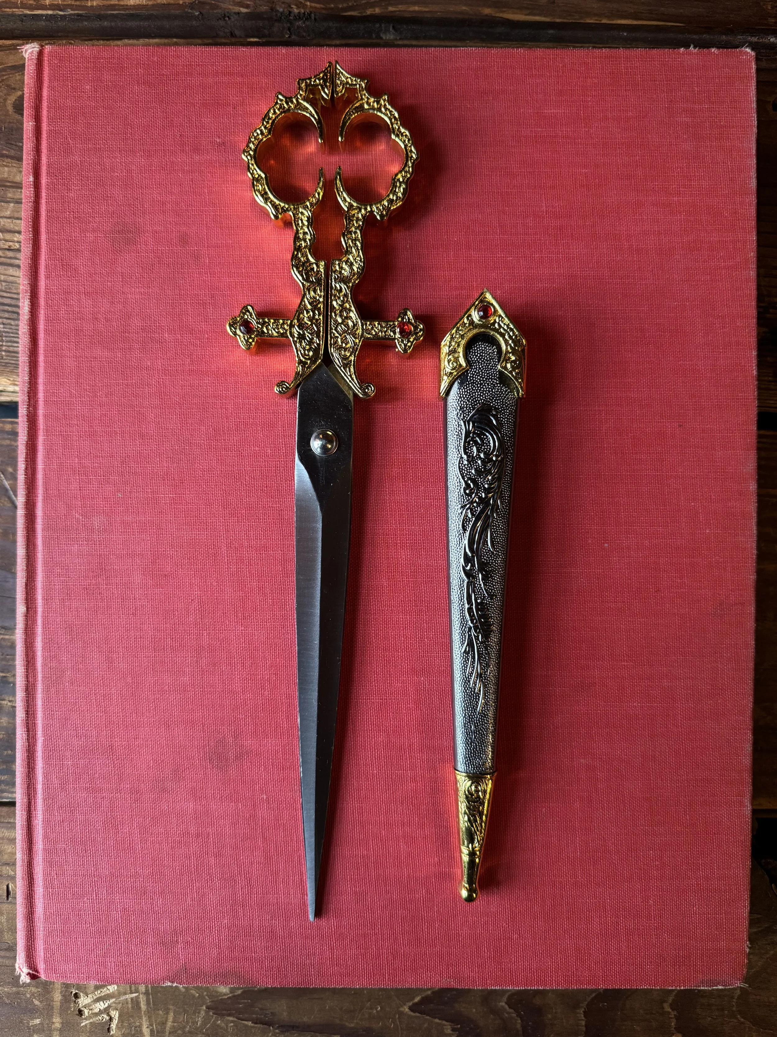 ornate black and gold with red gem detail scissors in sheath
