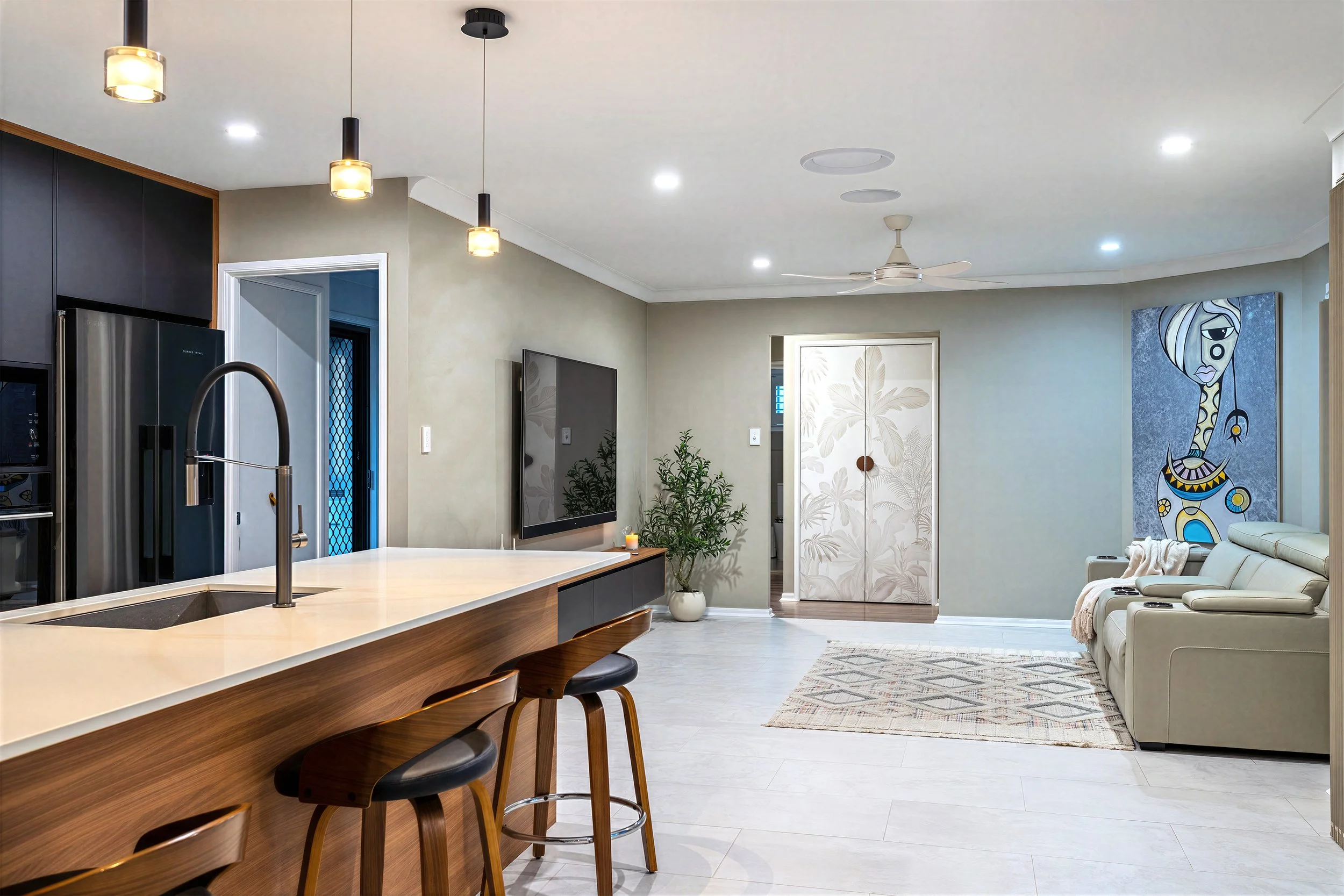 Open-plan kitchen at 13 Zac Avenue, Coombabah with island bench, pendant lighting, wall-mounted TV and living area beyond