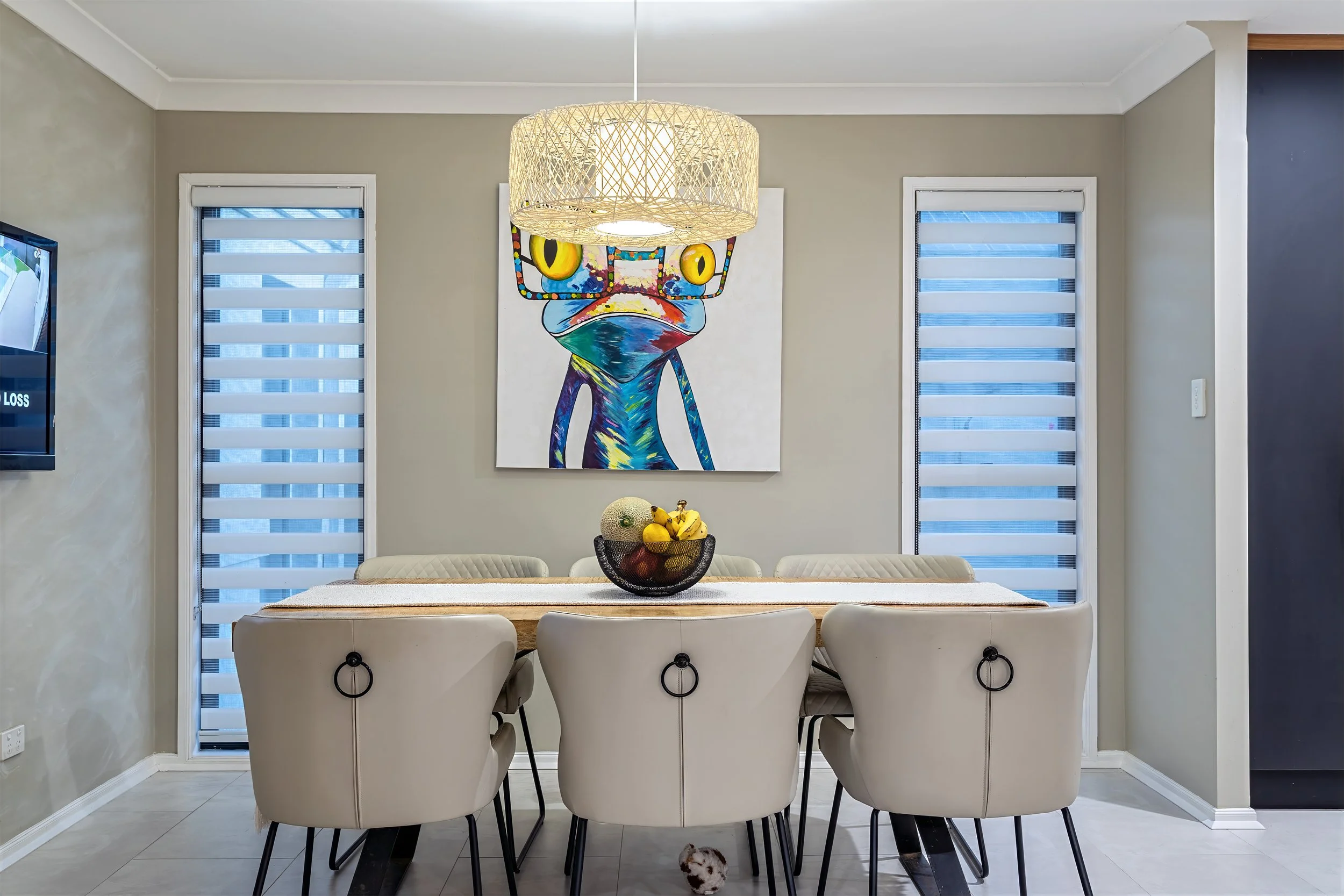 Dining area at 13 Zac Avenue, Coombabah with woven pendant light above a timber table and colourful feature artwork