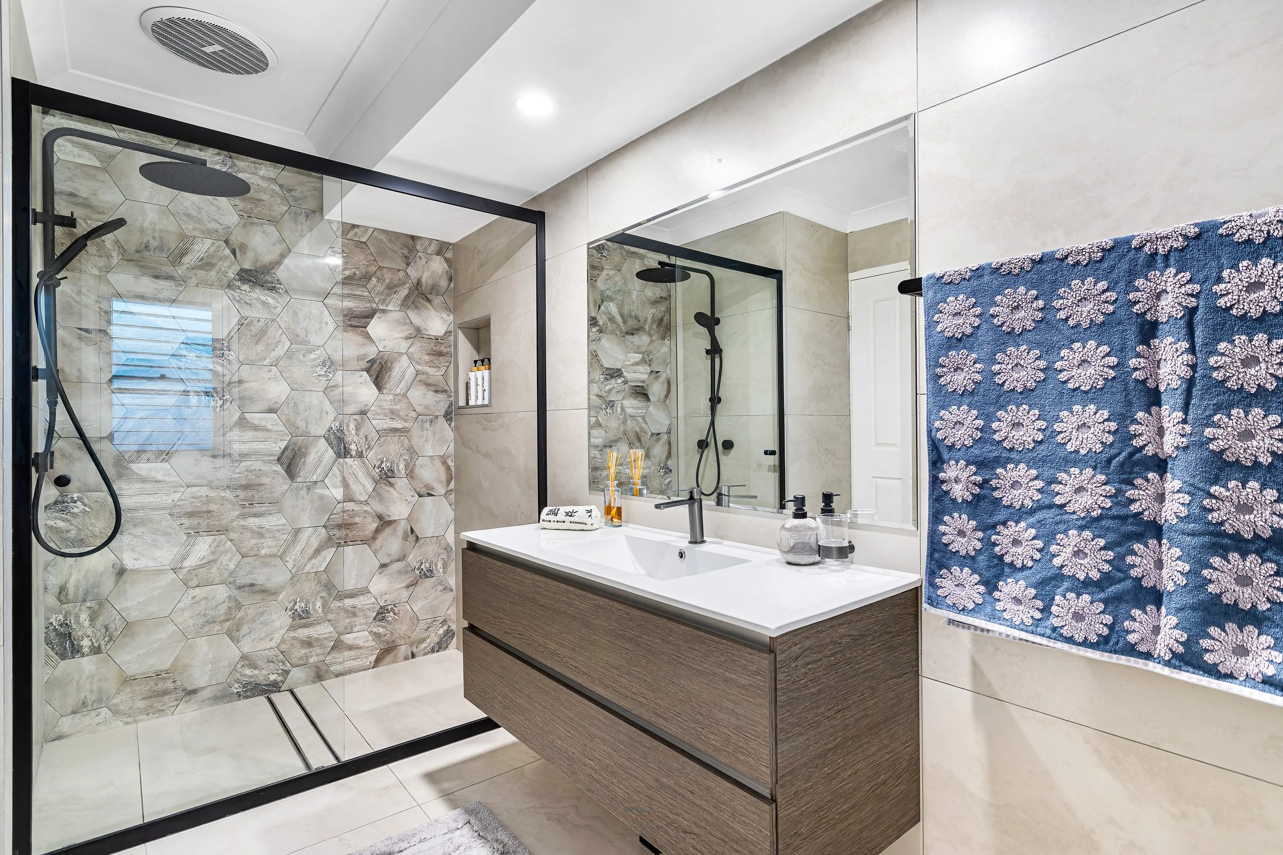  Ensuite bathroom at 13 Zac Avenue, Coombabah with hexagon-tiled walk-in shower and floating timber vanity 