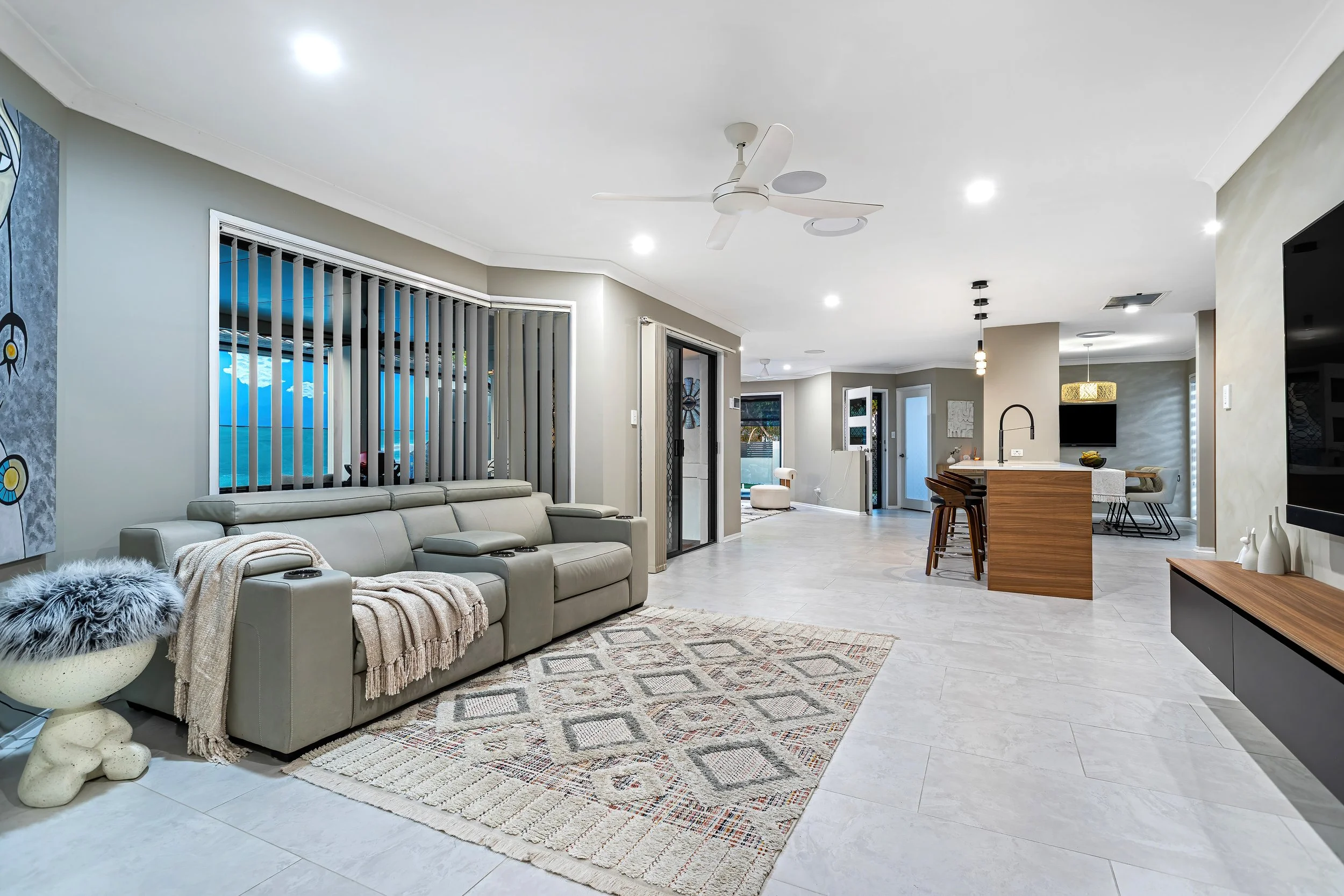  Open-plan living area at 13 Zac Avenue, Coombabah with grey sectional lounge and sightline through to the kitchen 