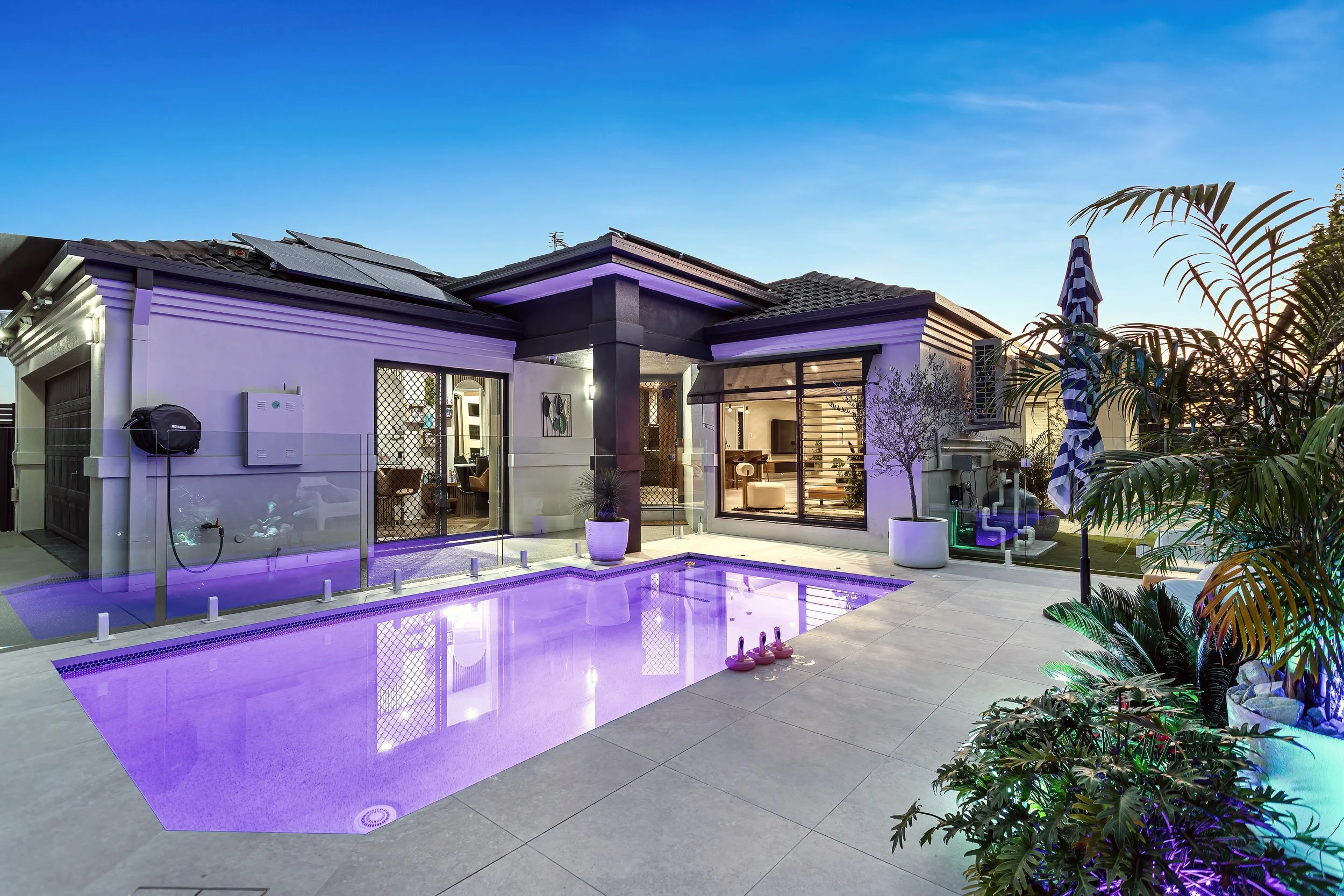  Twilight aerial view of 13 Zac Avenue, Coombabah showing the illuminated pool and solar panels 