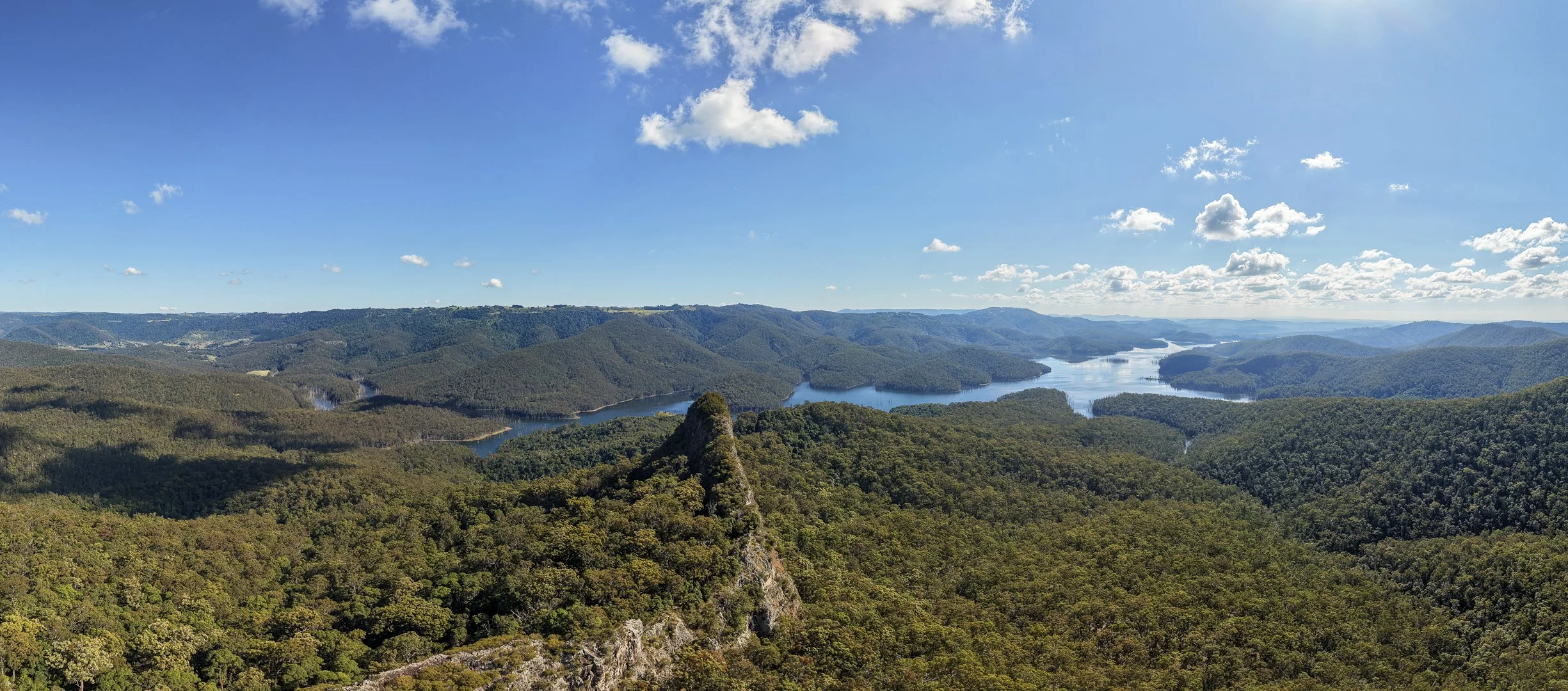 Panoramic drone aerial view of Hinze Dam reservoir and Gold Coast Hinterland mountain peaks in Advancetown