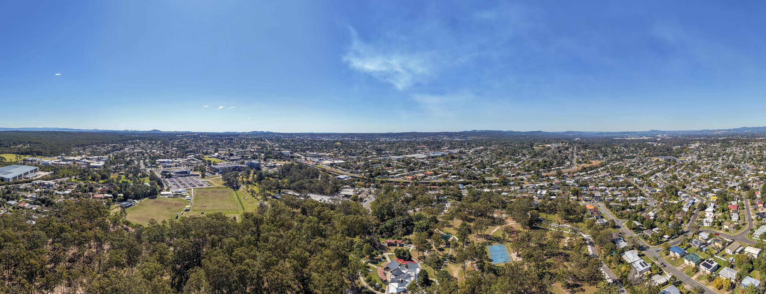 Aerial view over Logan Central QLD, showing residential streets, parkland and the town centre in the distance