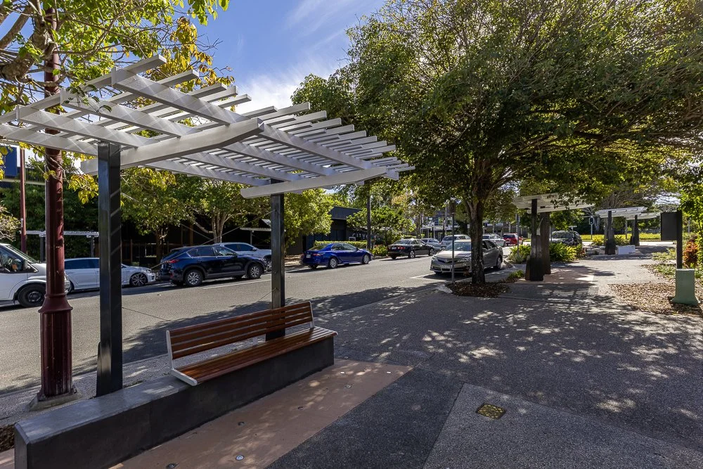 Shaded pedestrian seating area and modern streetscape view along Fitzgerald Avenue in Springwood, QLD.