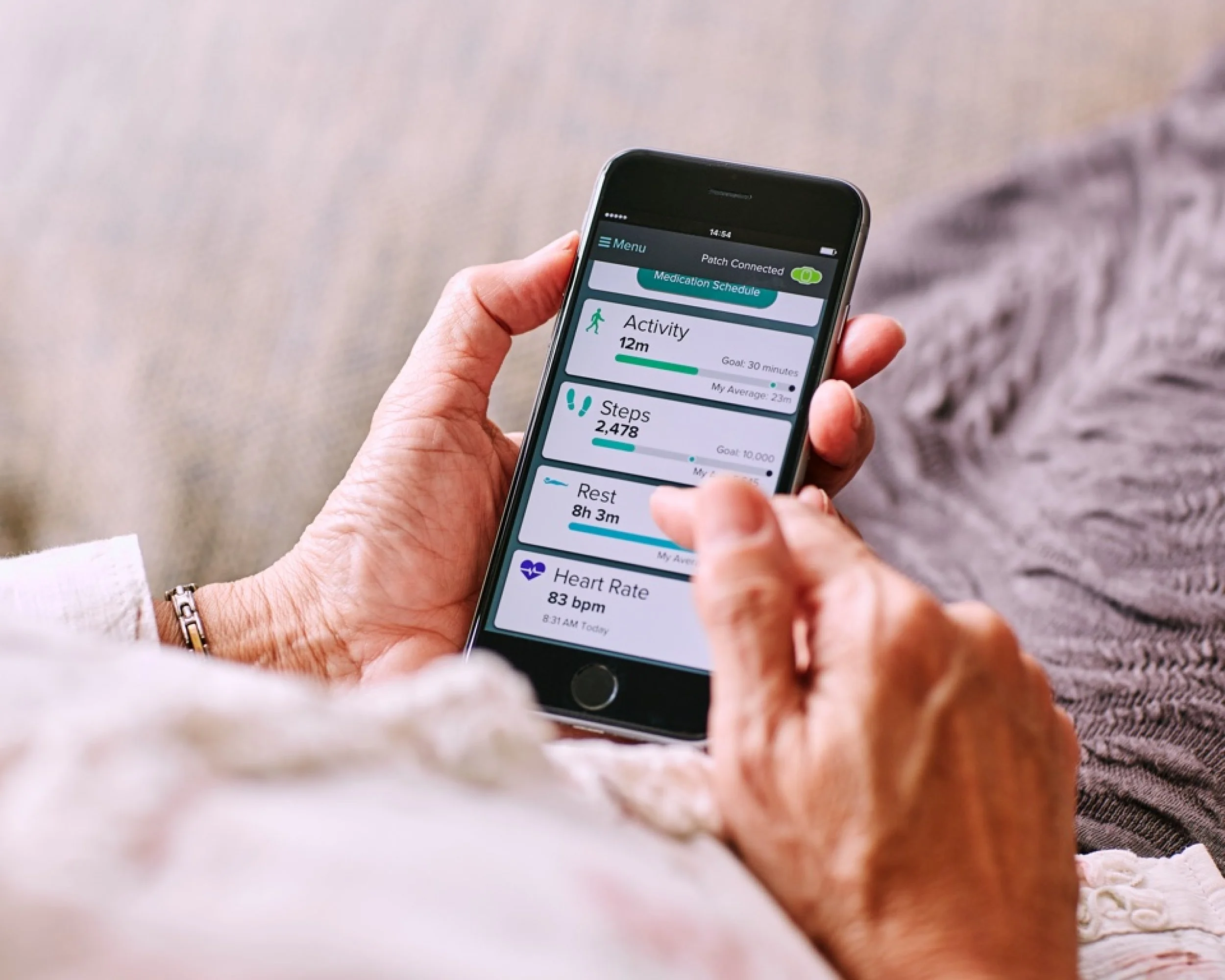 Close-up of a person's hand holding a smartphone displaying a health and activity tracking app, showing activity, steps, rest, and heart rate data.