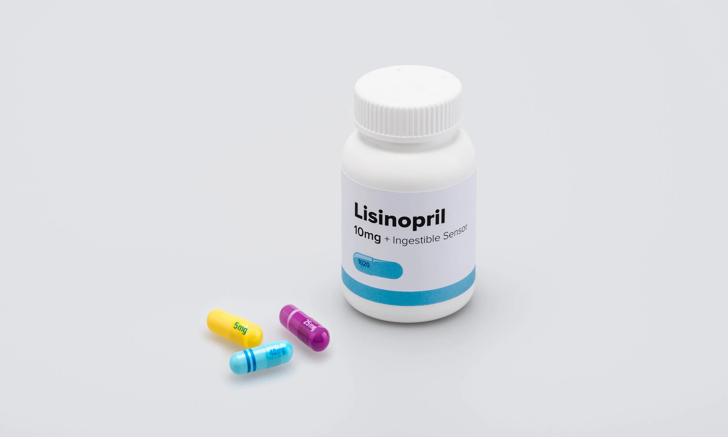 A white bottle labeled "Lisinopril 10mg + Ingestible Sensor" with four colorful capsules in front of it on a plain white background.