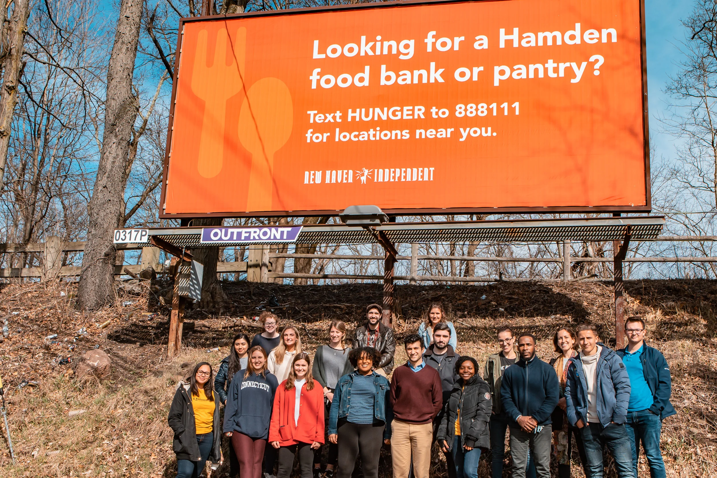 Students and professors pose in front of one of the billboards on Dixwell Avenue.