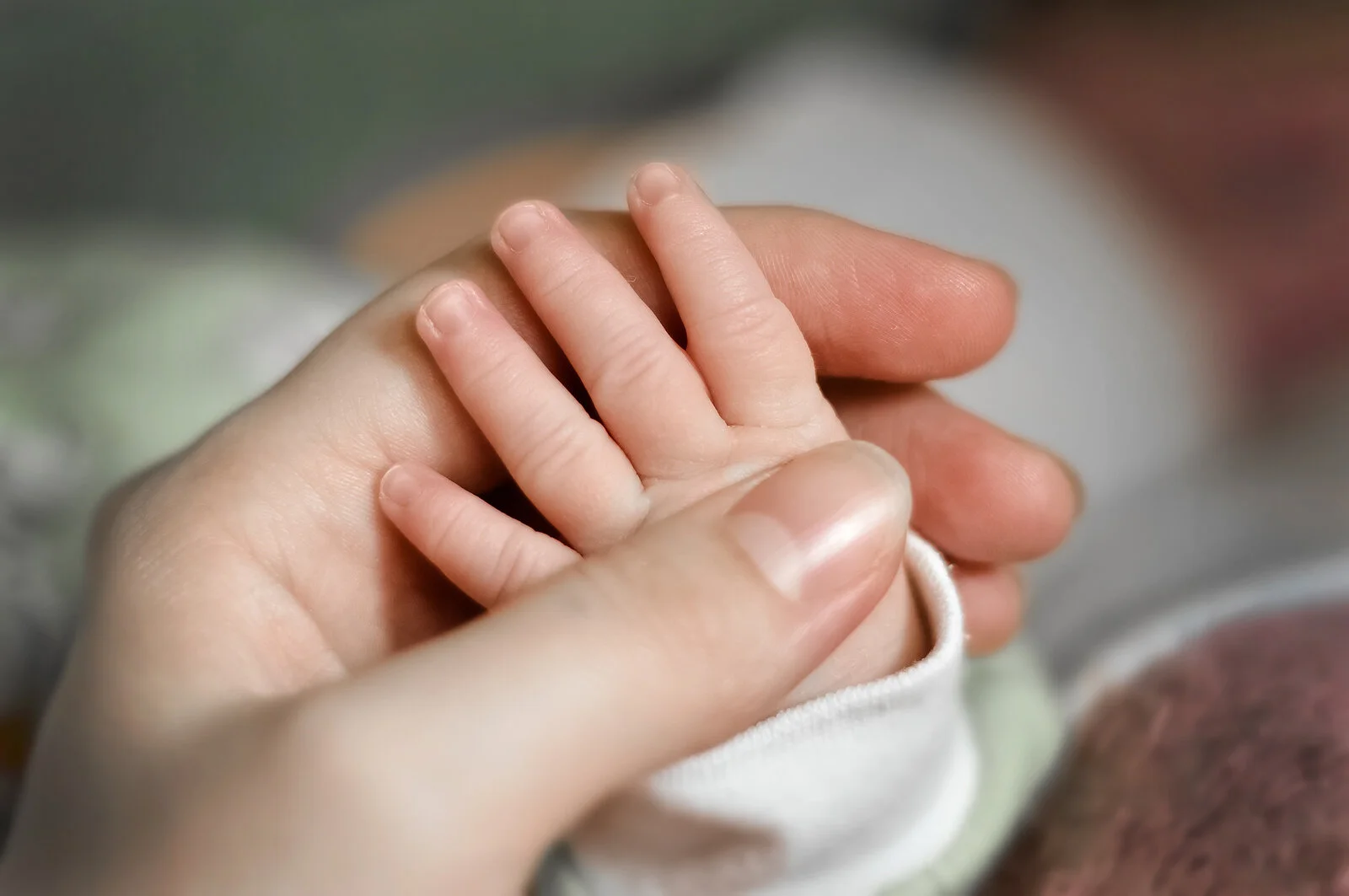 A close-up of a mother holding a newborn hand. Online postpartum support in Louisiana can help you overcome anxiety and depression symptoms. Learn more about trauma therapy or therapy for moms in Louisiana today.