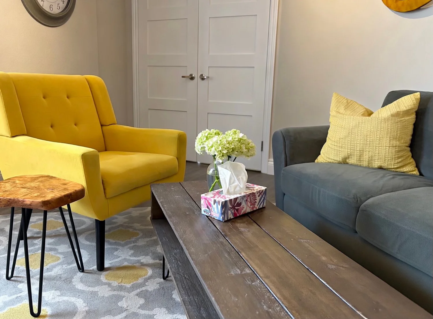 Yellow armchair and grey sofa around a coffee table in the Journeys office in Aurora.