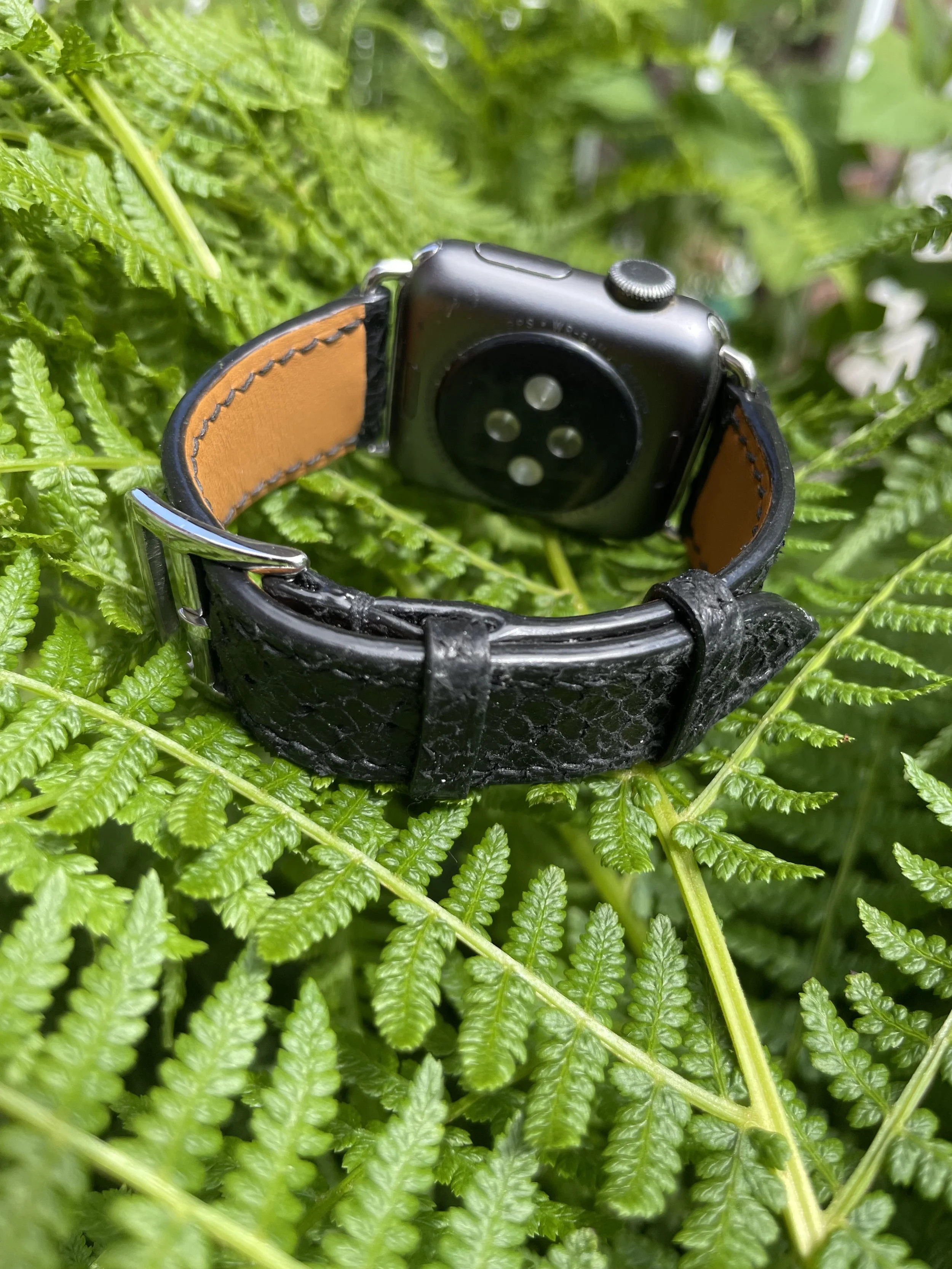 A apple watch with black fish leather watch band