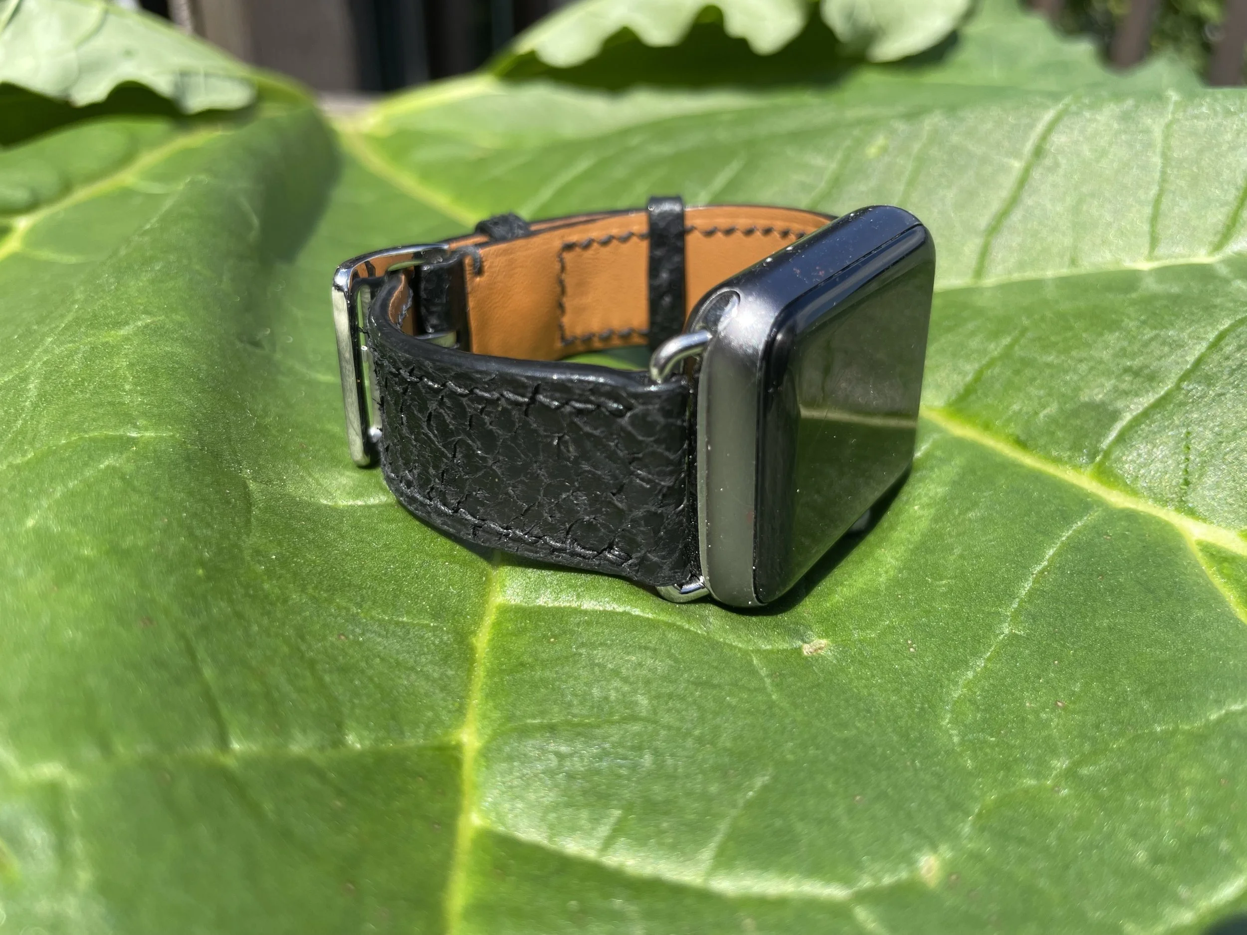 A apple watch with black fish leather watch band