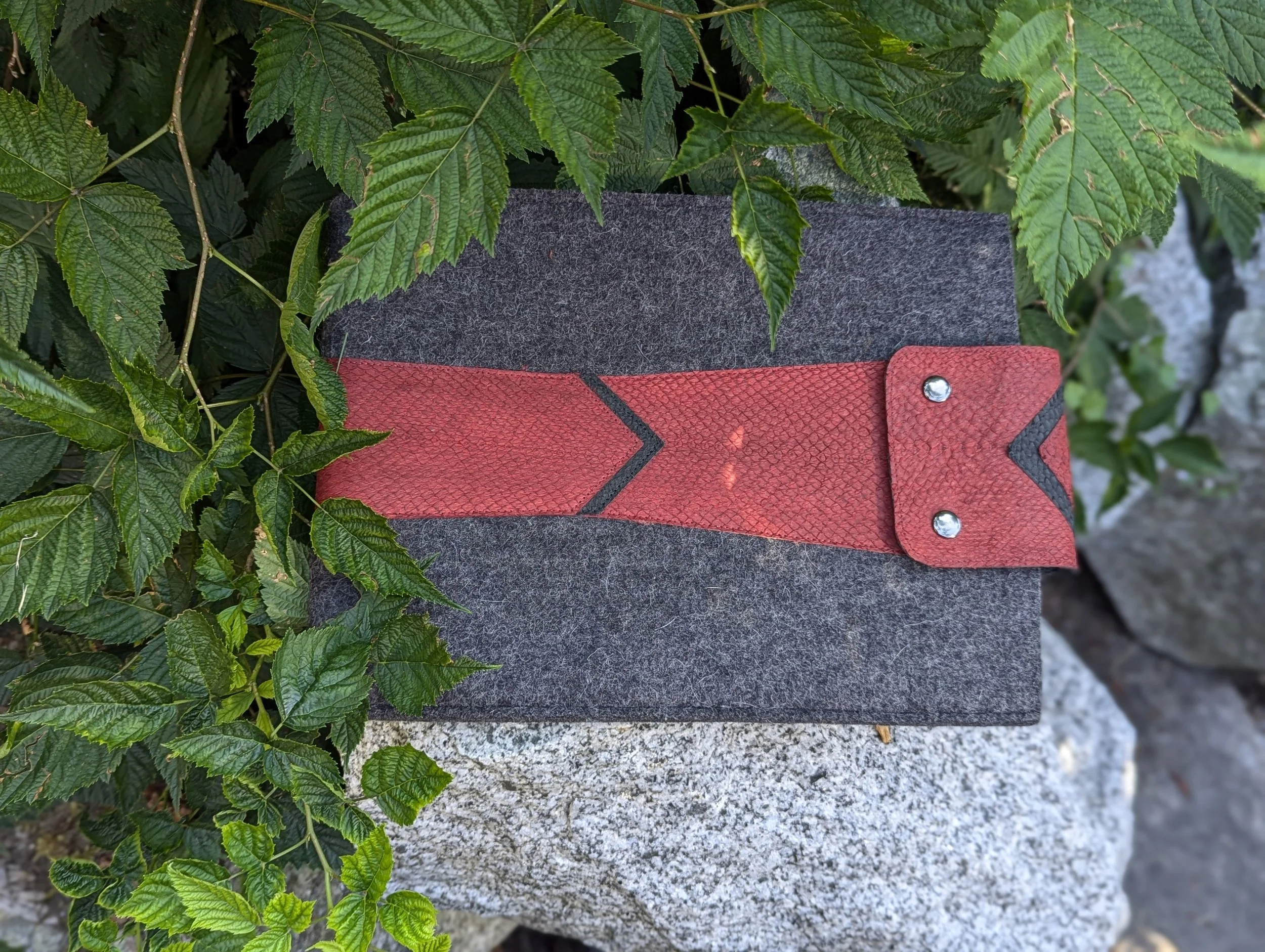 A felted wool laptop case with red and black fish leather closure
