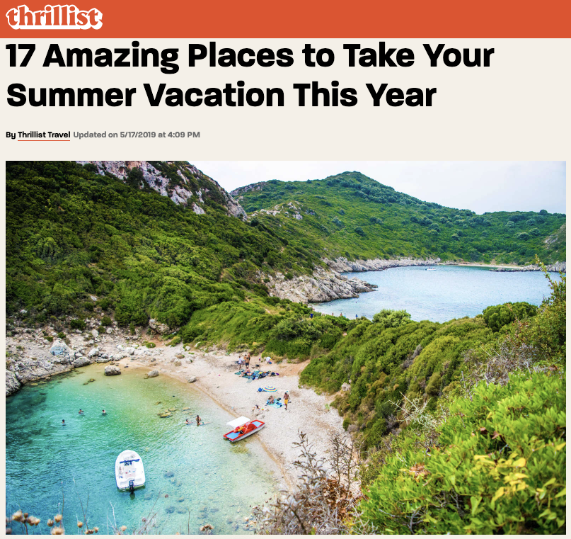 Image Description: a picture of two coved beaches surrounded by mountains with people on the sand and boats in the water.