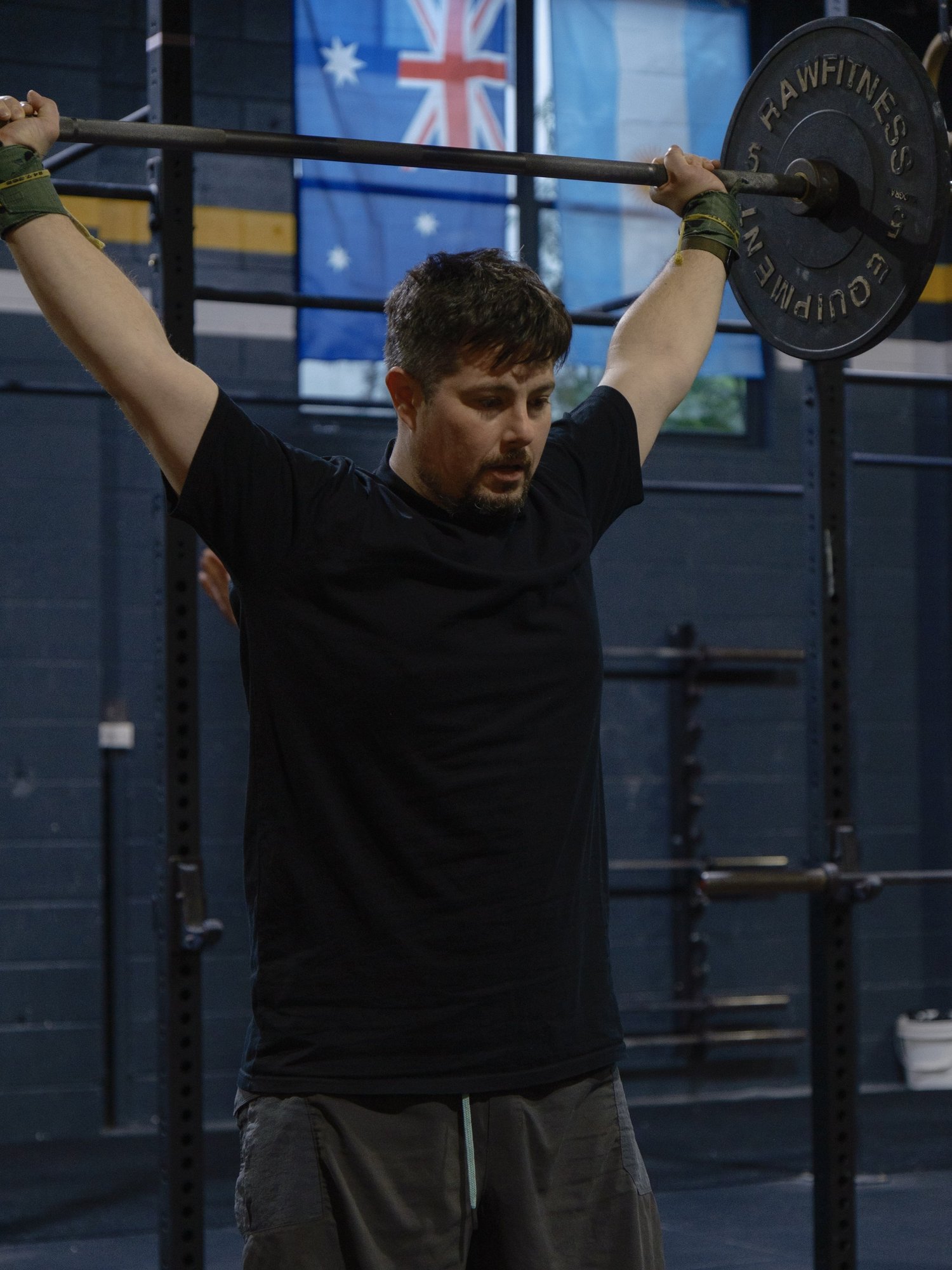 Member holding a barbell overhead in a CrossFit class
