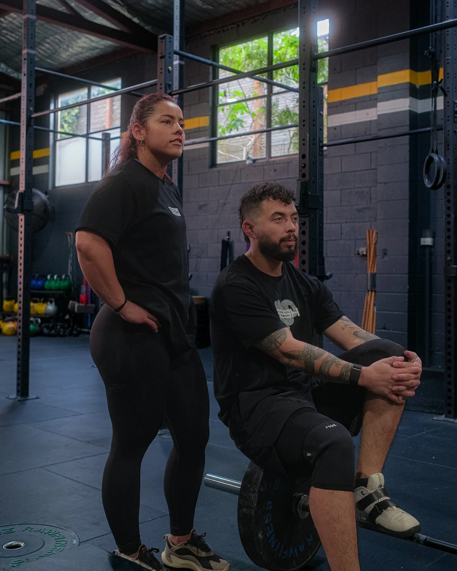 Two members at the gym, one sitting on a loaded barbell