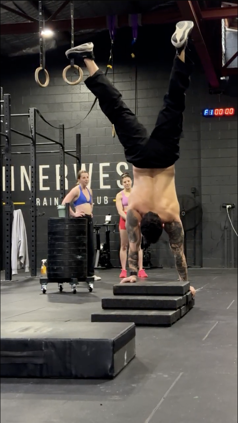 Member doing a handstand while others watch at a Saturday session