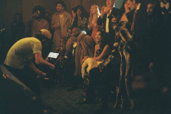 Group of people at a social event, some holding drinks, with a photographer taking pictures in the foreground.
