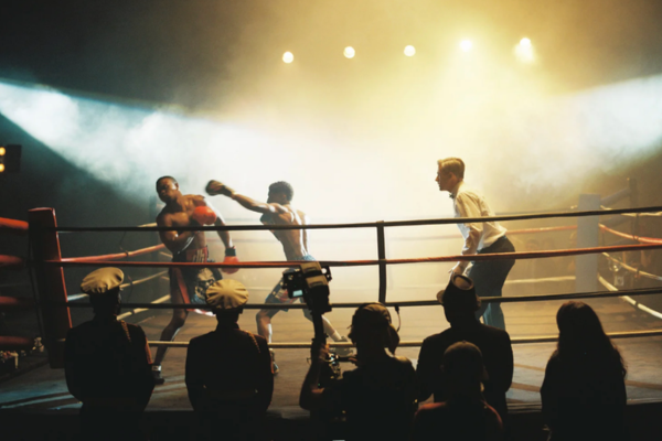 Boxers sparring inside a boxing ring with an audience watching